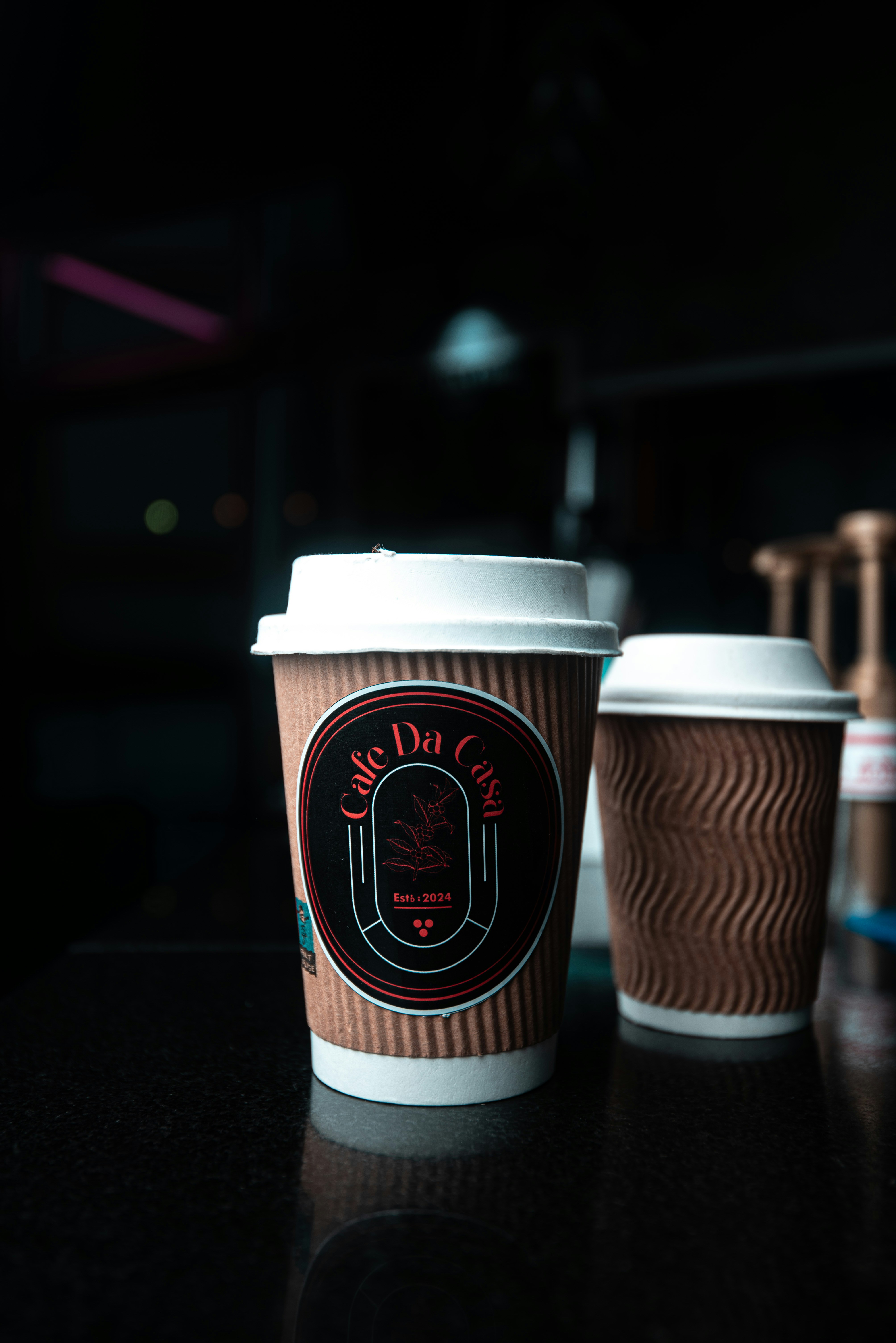 Two coffee cups on a dark table.