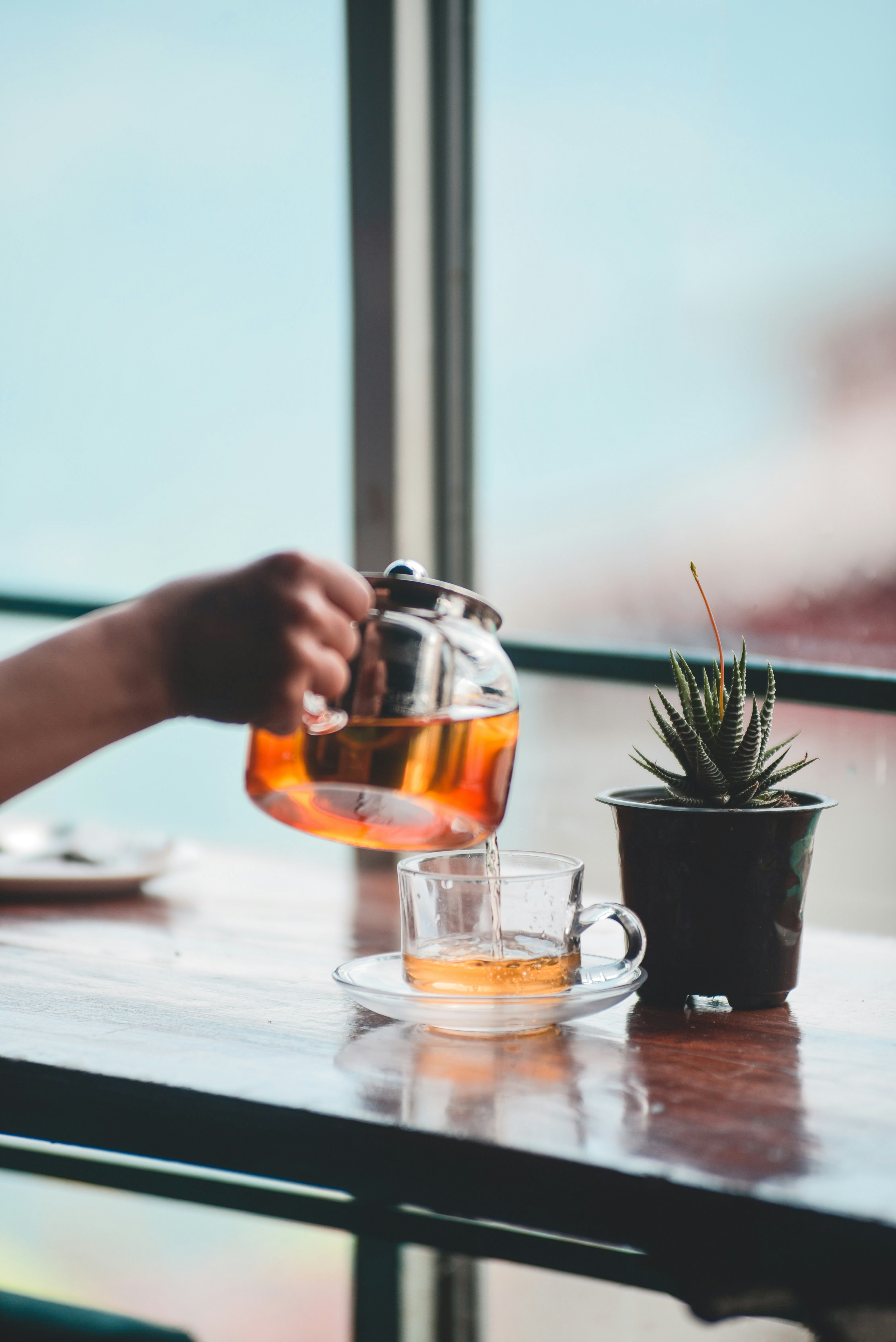 Pouring tea into a glass cup.