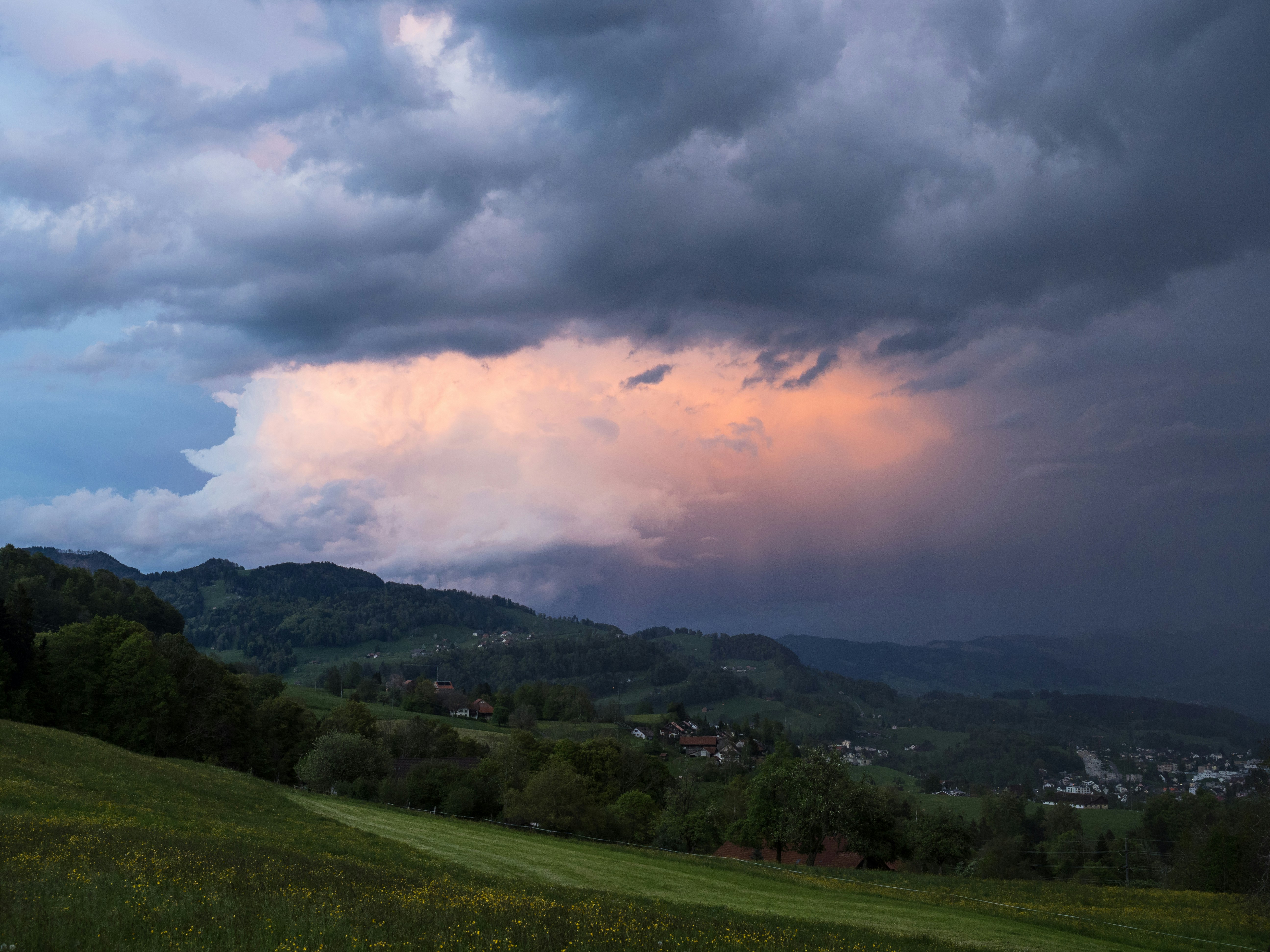 Storm clouds gather above the green mountains.