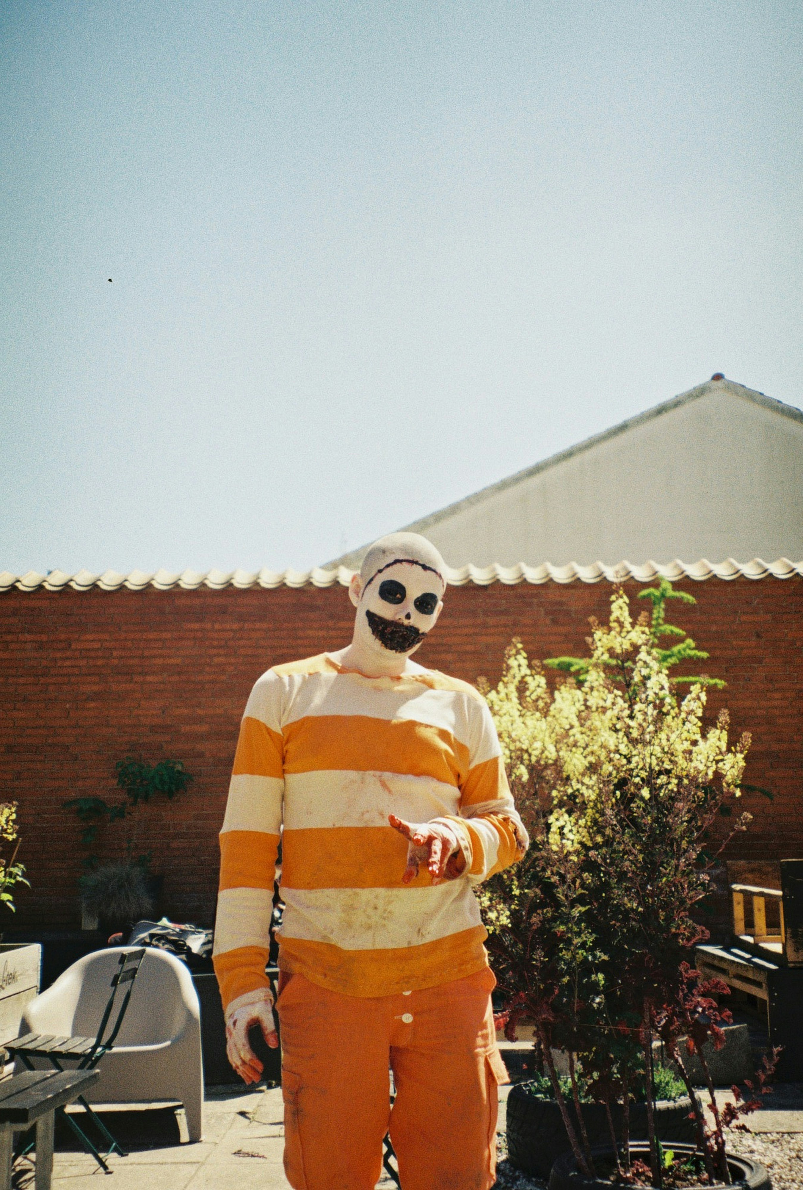 A person in a scary mask stands outside.
