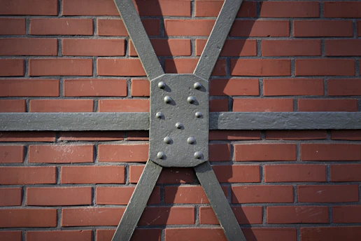 Metal bracing is attached to a red brick wall.