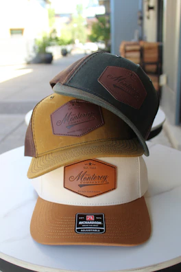 Three hats with "monterey" logos are stacked.