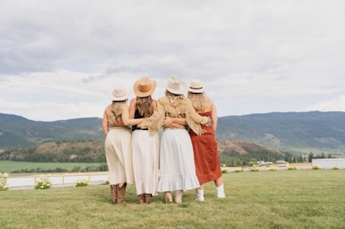 Four friends embrace, overlooking a scenic landscape.