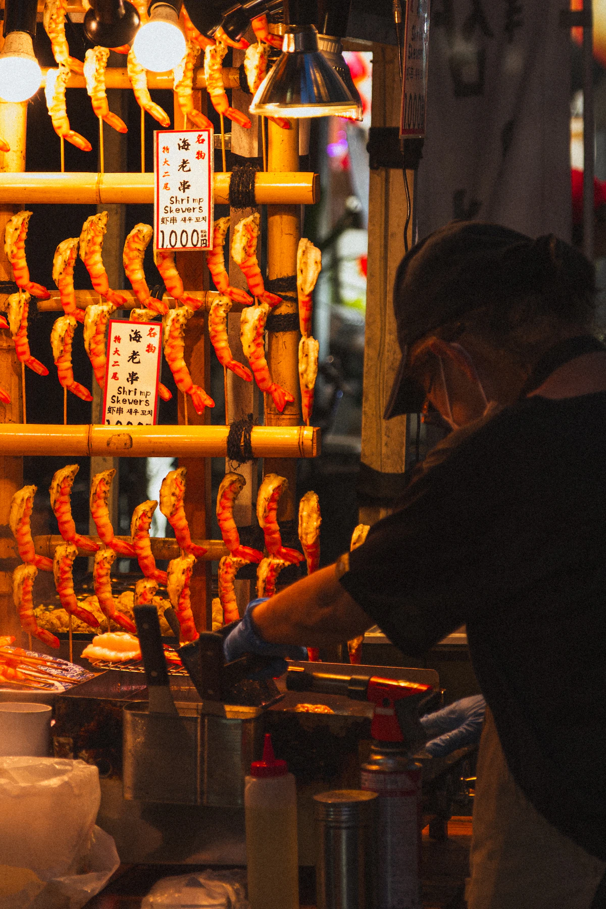 Cook grilling shrimp at a Japanese street stall
