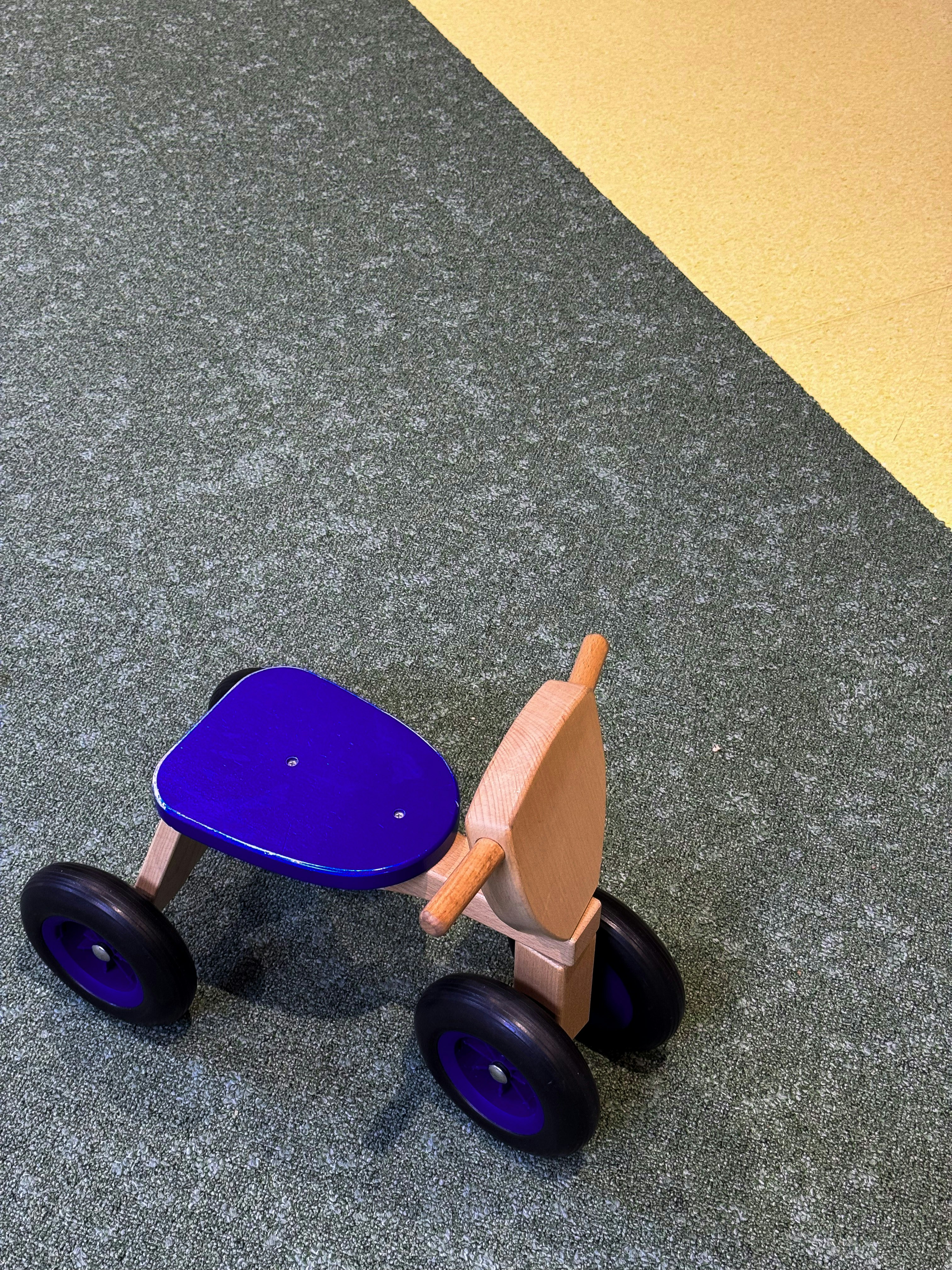 Wooden toy vehicle with dark blue and black details.