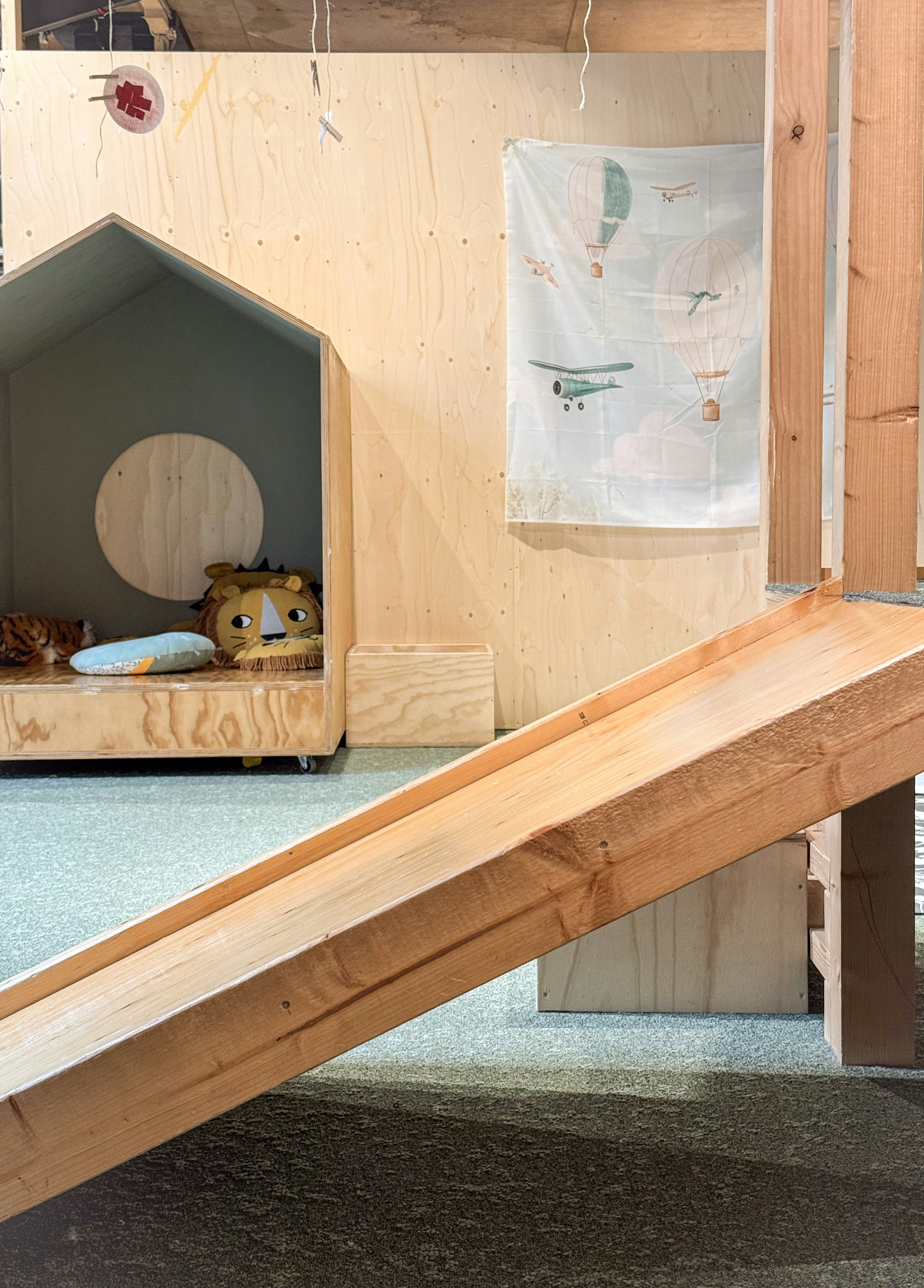 A wooden playhouse with a slide and a house.