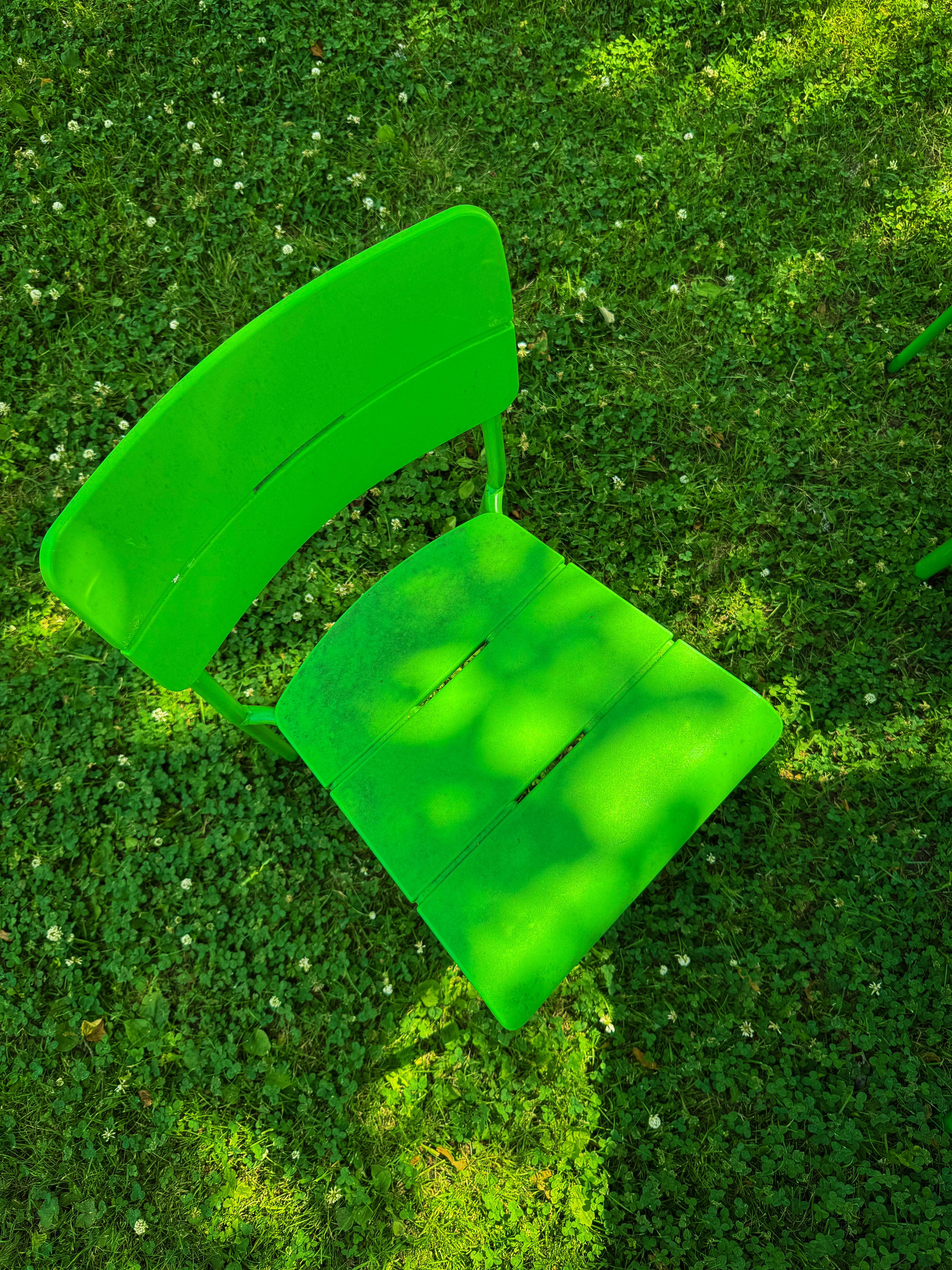 A green chair sits on lush green grass.