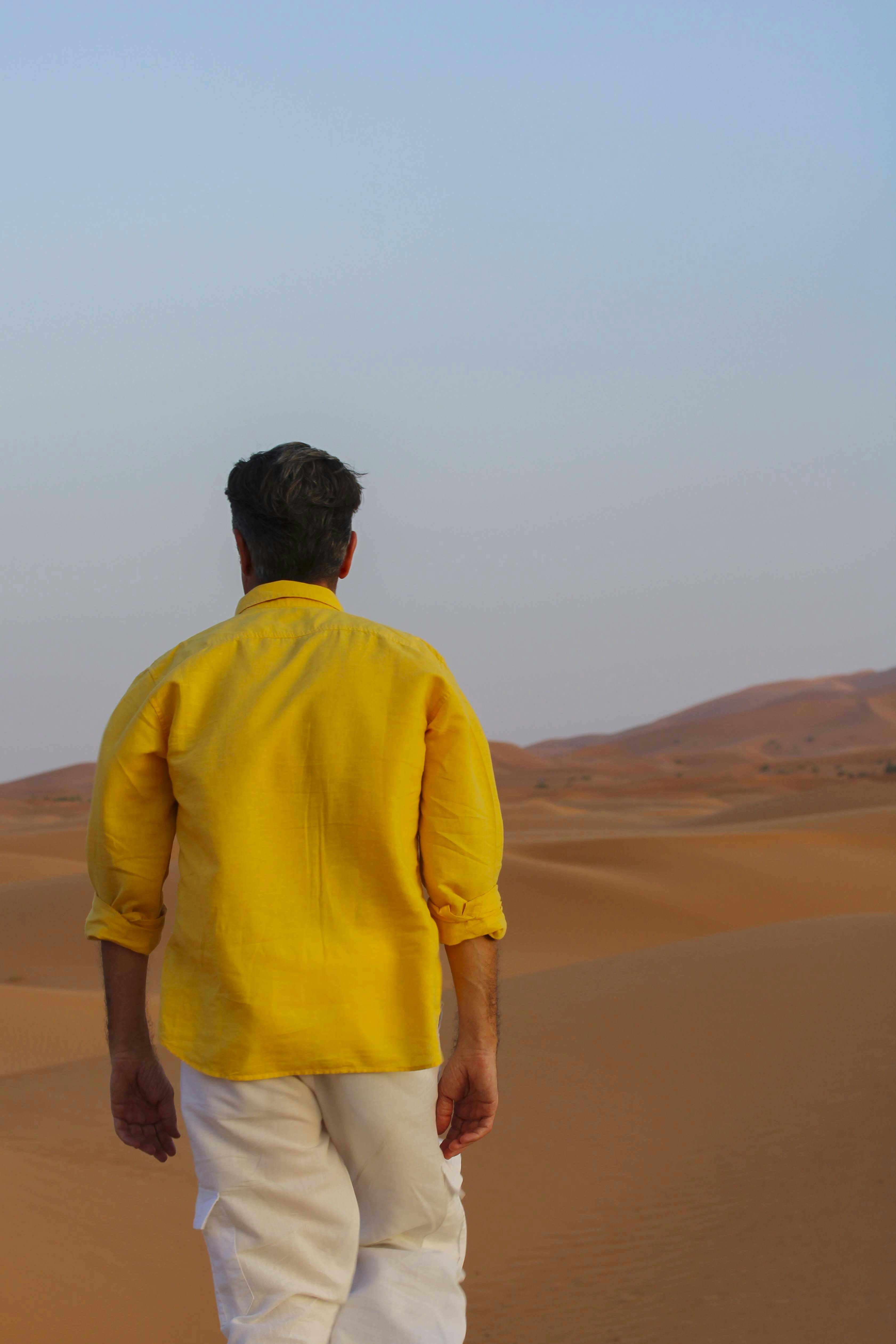 Man in yellow shirt looks out over the desert.