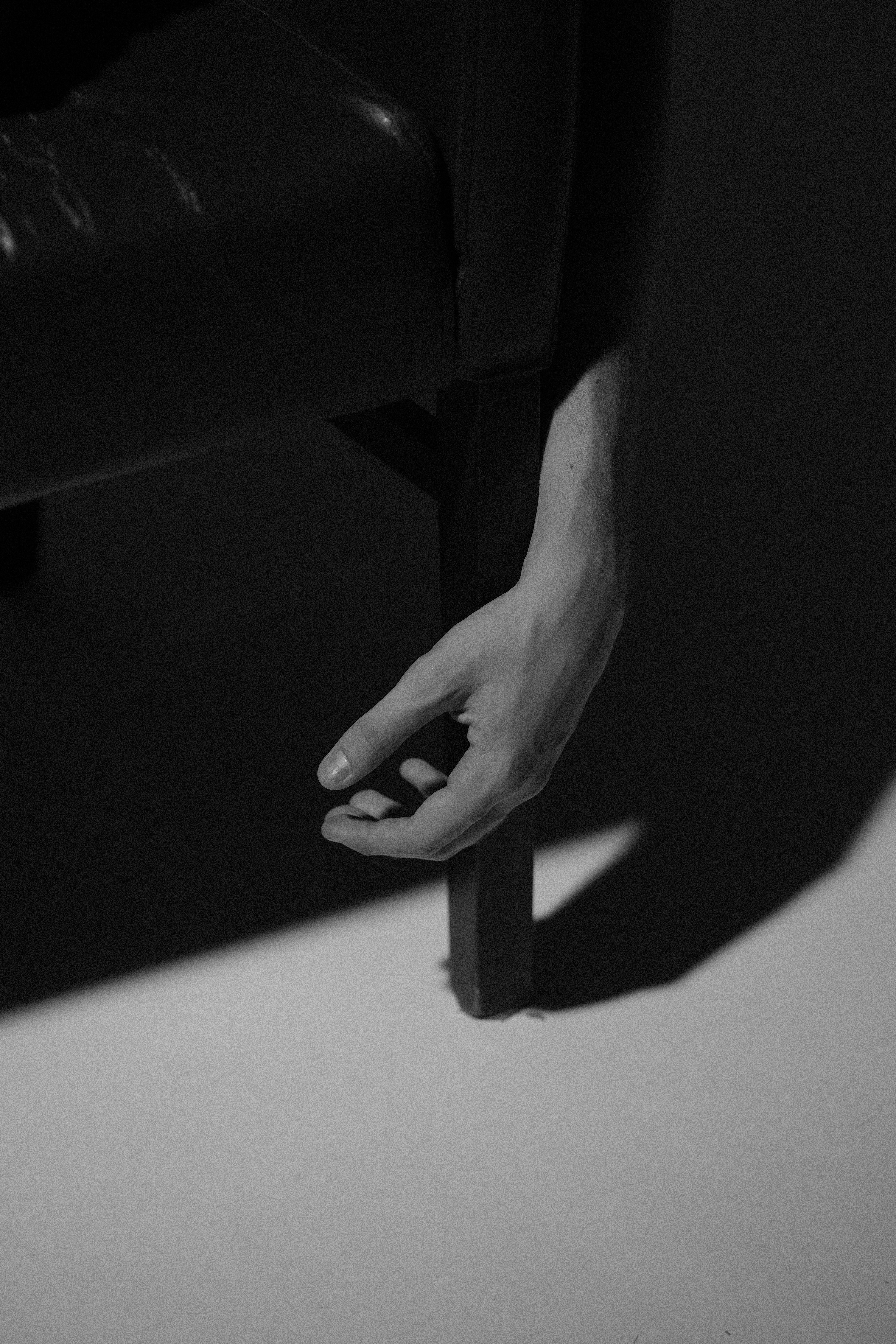 A hand dangles from a darkened chair.