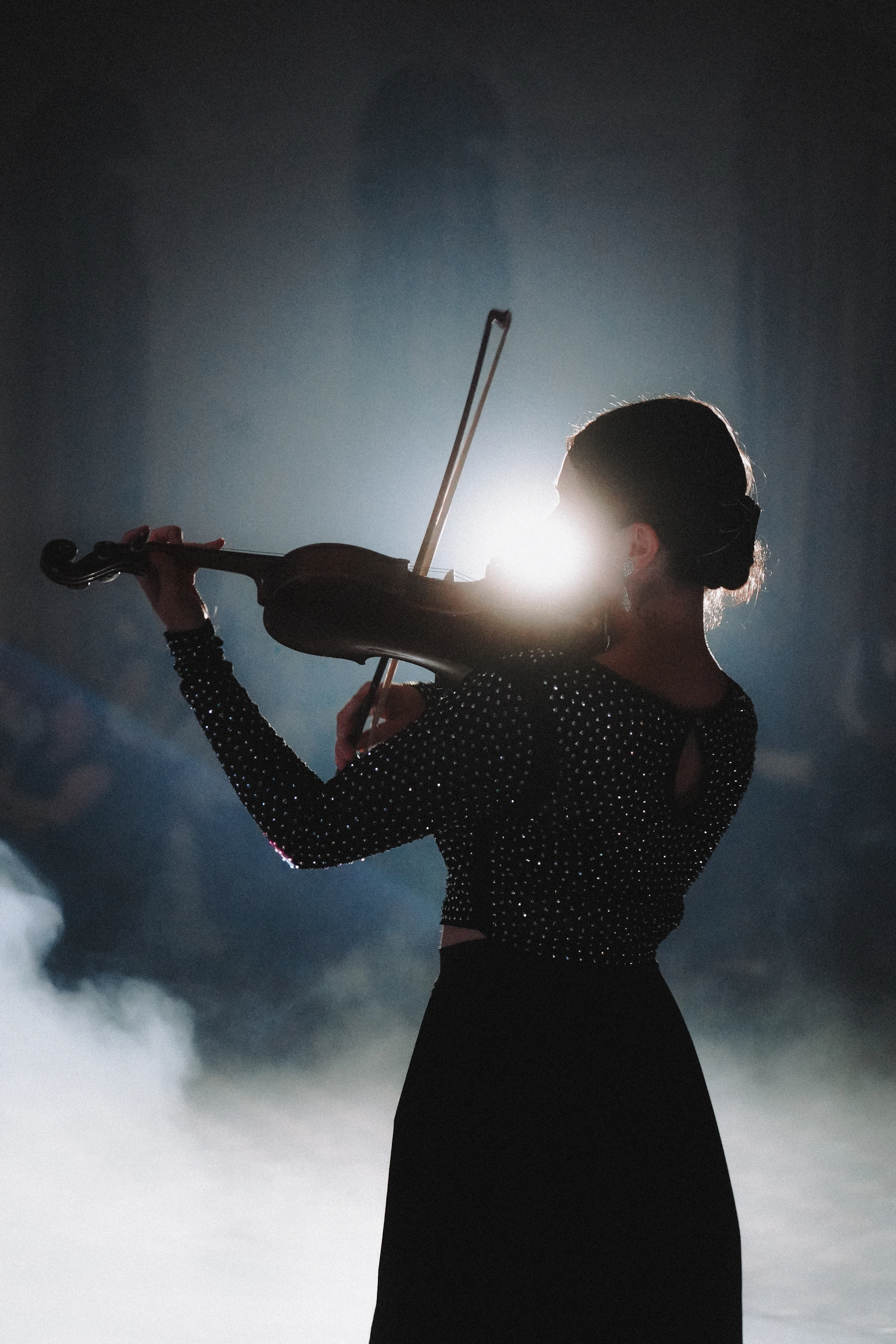 A violinist plays in the spotlight and smoke