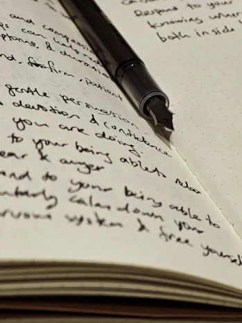 A fountain pen rests atop handwritten journal entries.