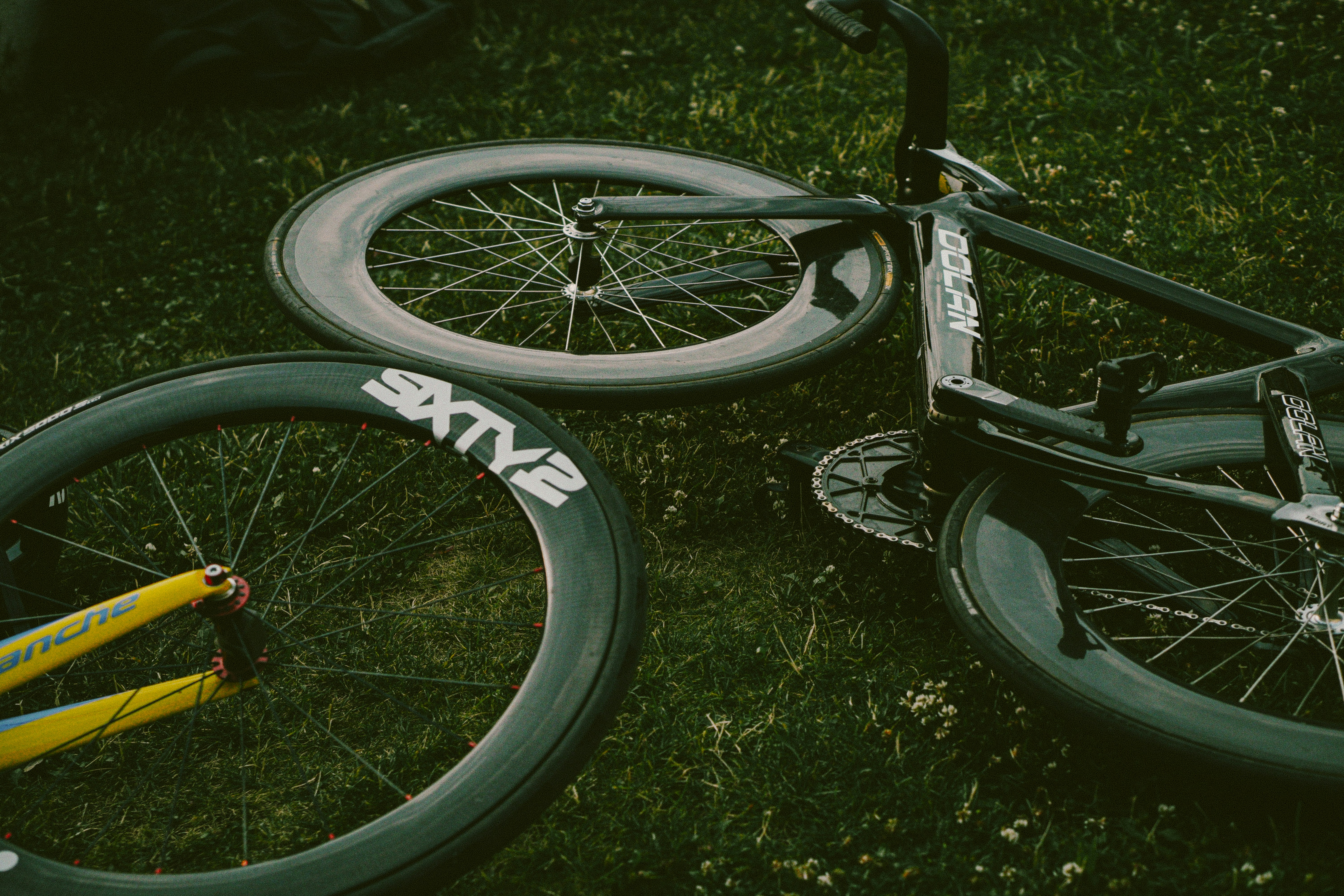 A bicycle lying on the grass with its wheels removed