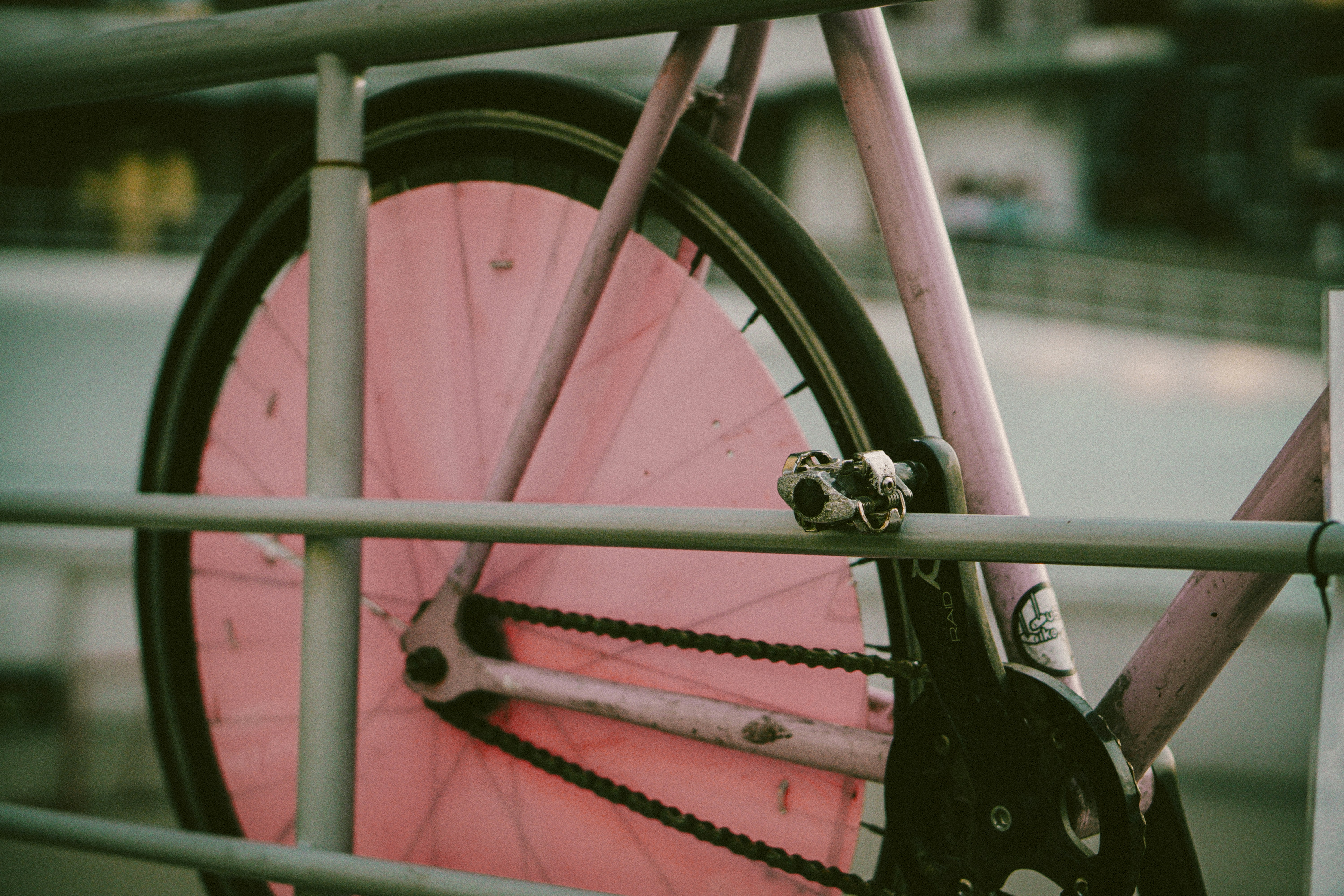 A pink bicycle wheel leaning against a railing