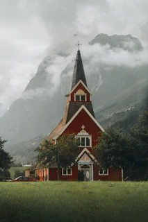 Red church stands before a majestic mountain landscape.