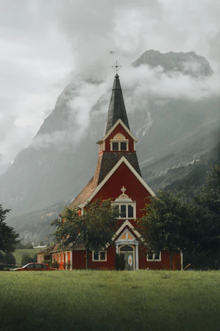 Red church stands before a majestic mountain landscape.