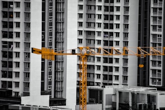 A construction crane stands before tall apartment buildings.