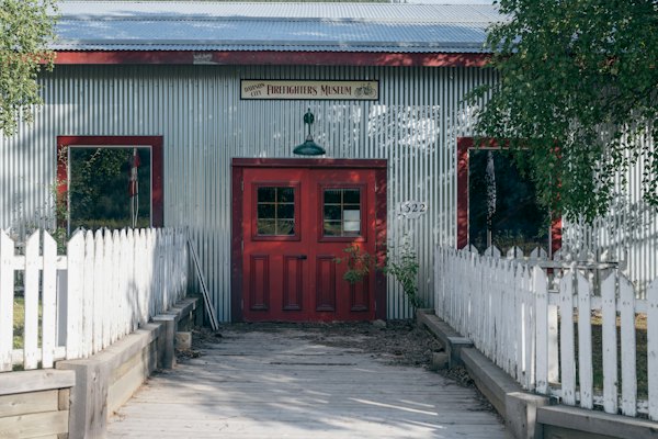 A red door behind a white picket fence — Dawson City, Canada