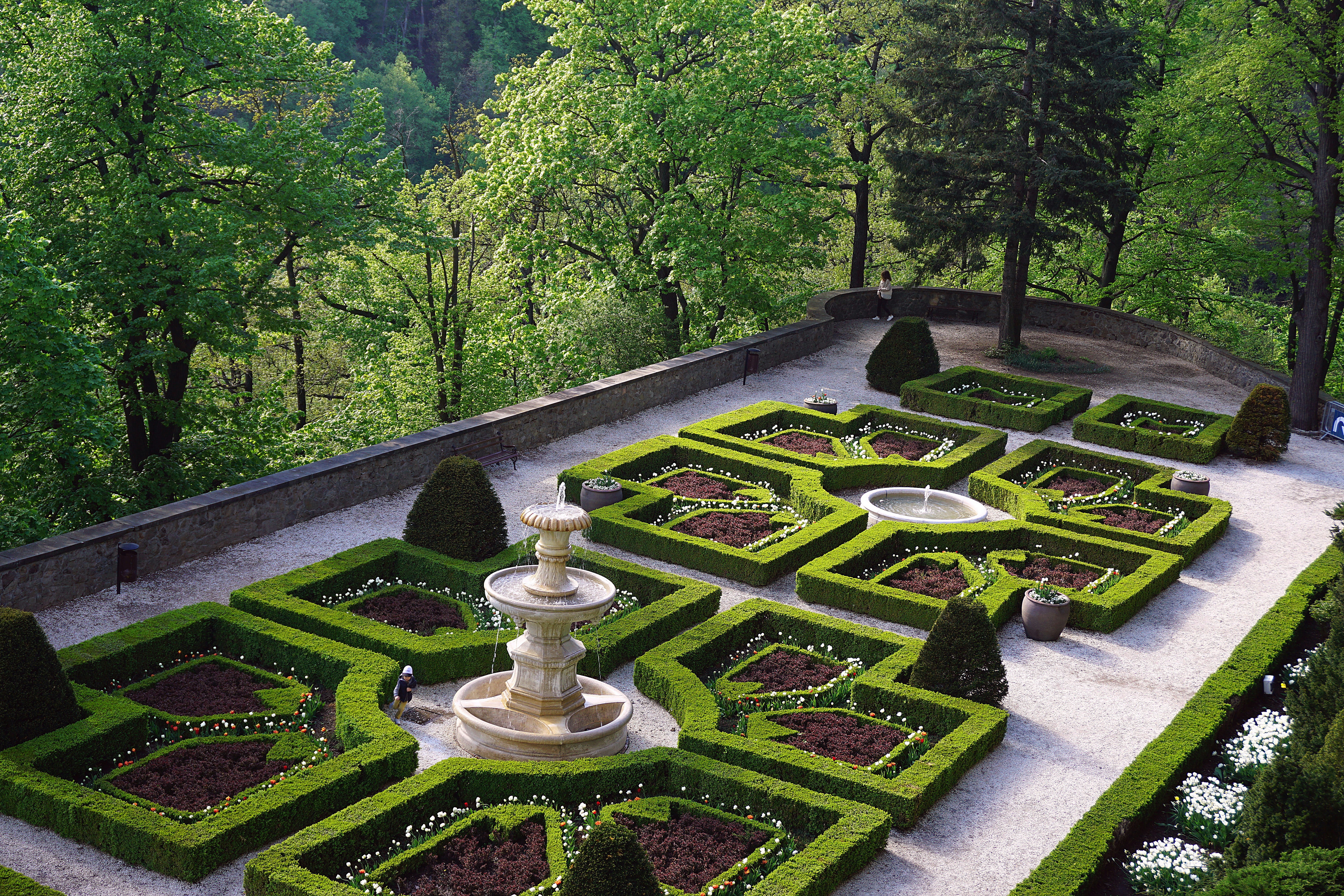 Formal garden with neatly trimmed hedges and fountain.