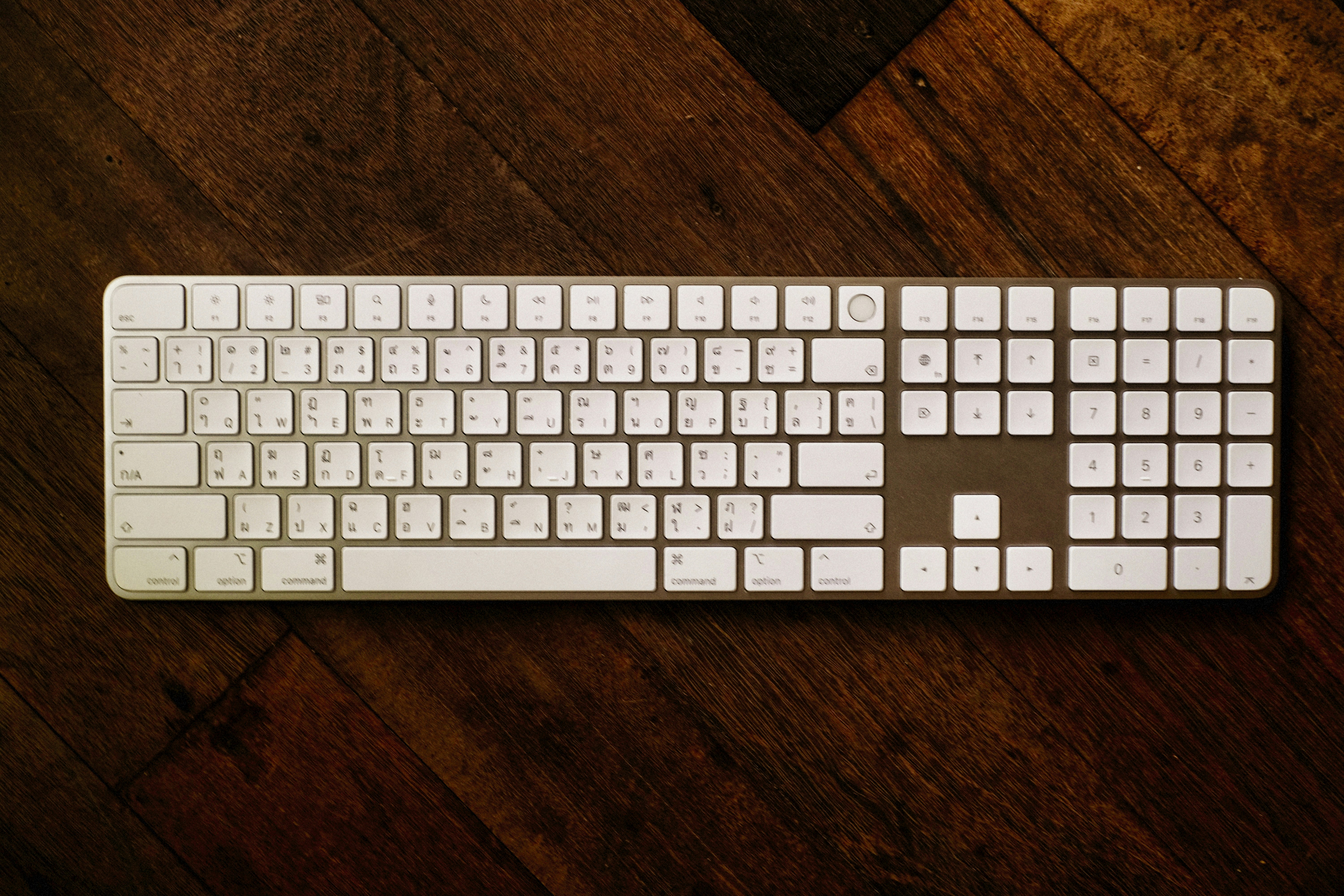 Um teclado de computador branco repousa sobre madeira.