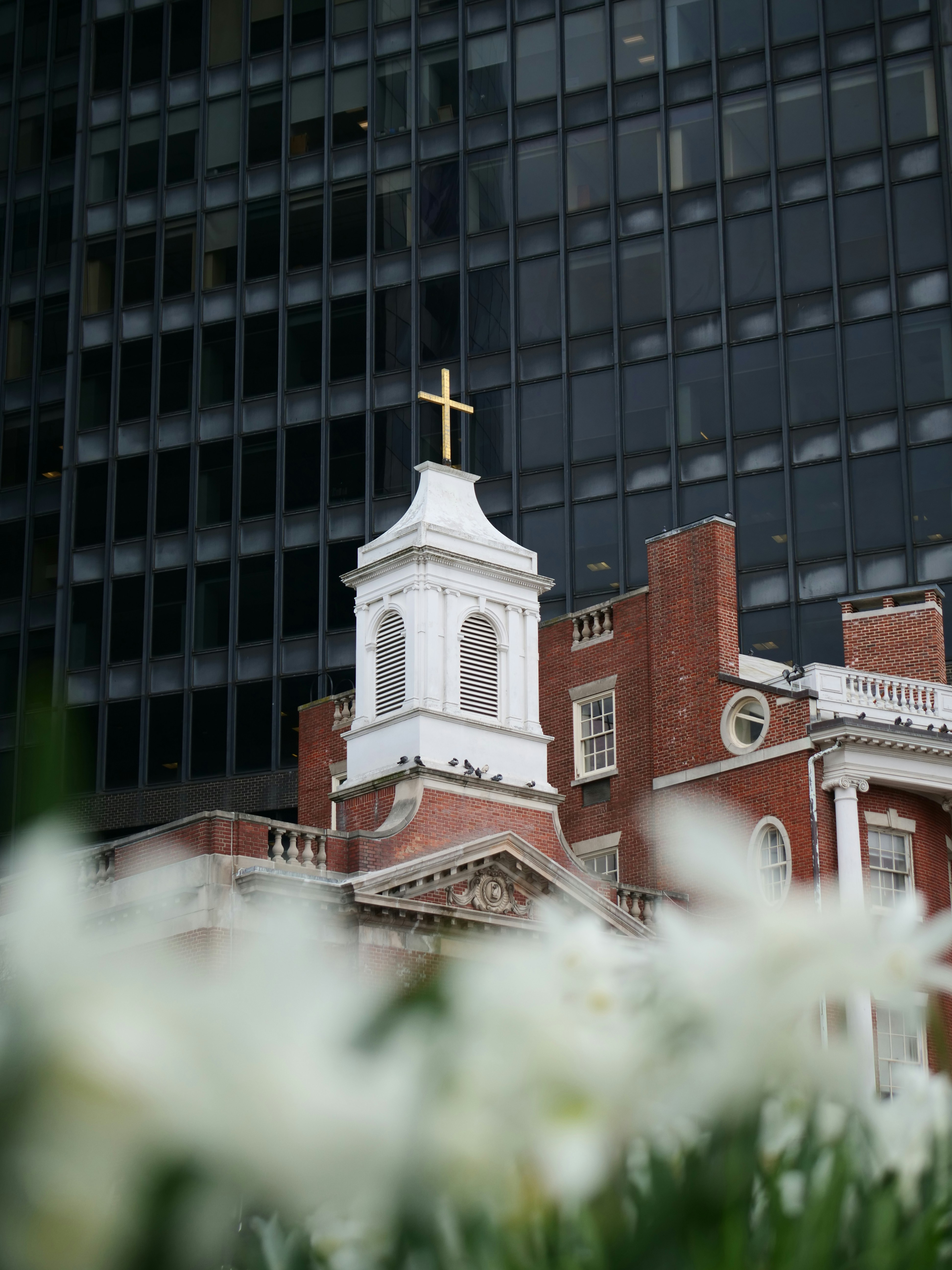 Church tower with a cross set against a building.