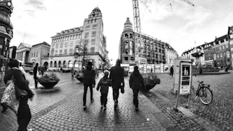 People walk along a city street with buildings.