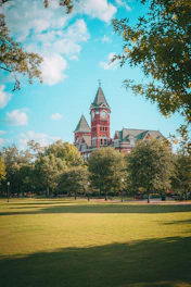 A historic building stands amidst lush trees.