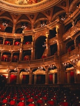 An ornate theater with empty red seats.