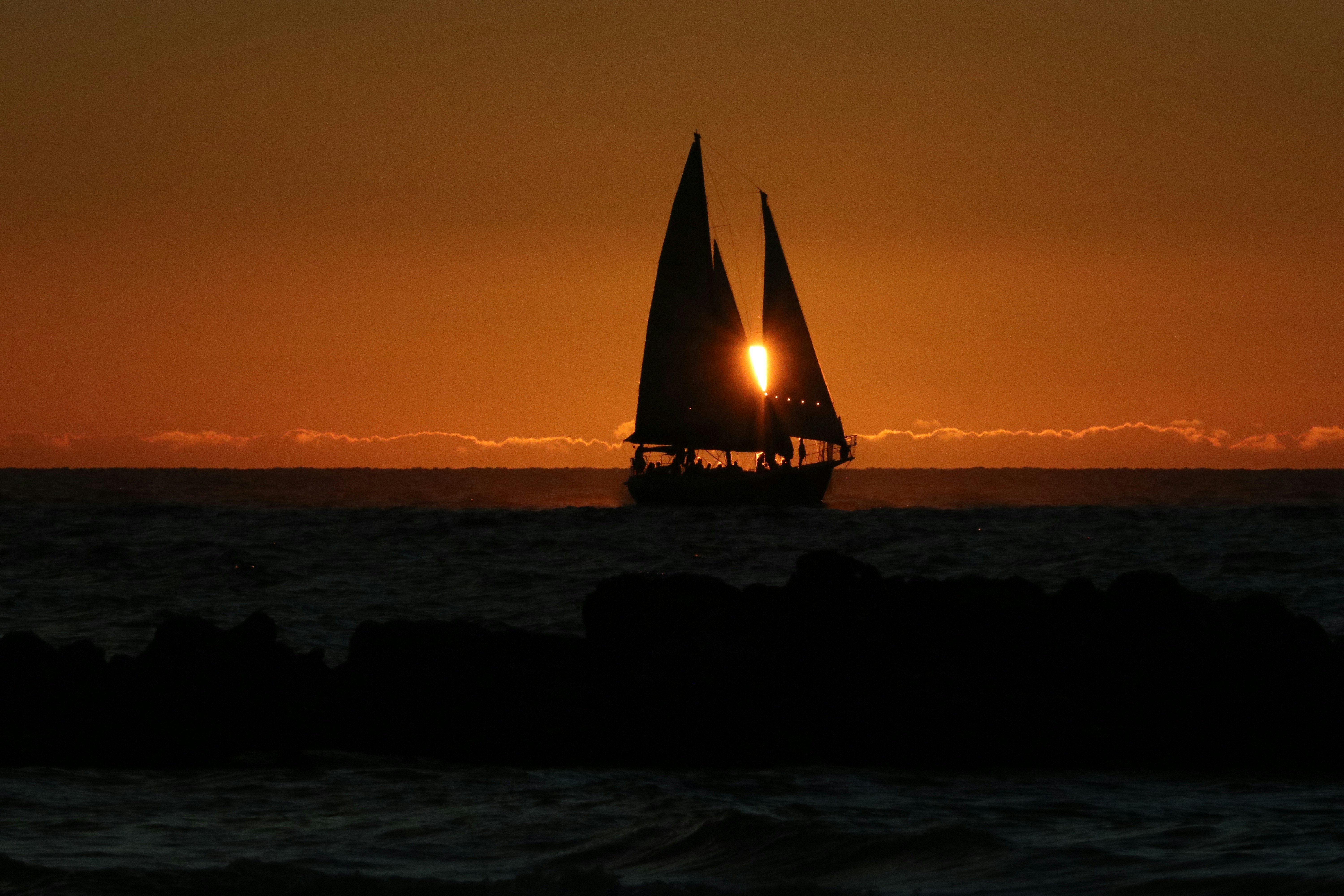 Die Silhouette eines Segelboots bei Sonnenuntergang.