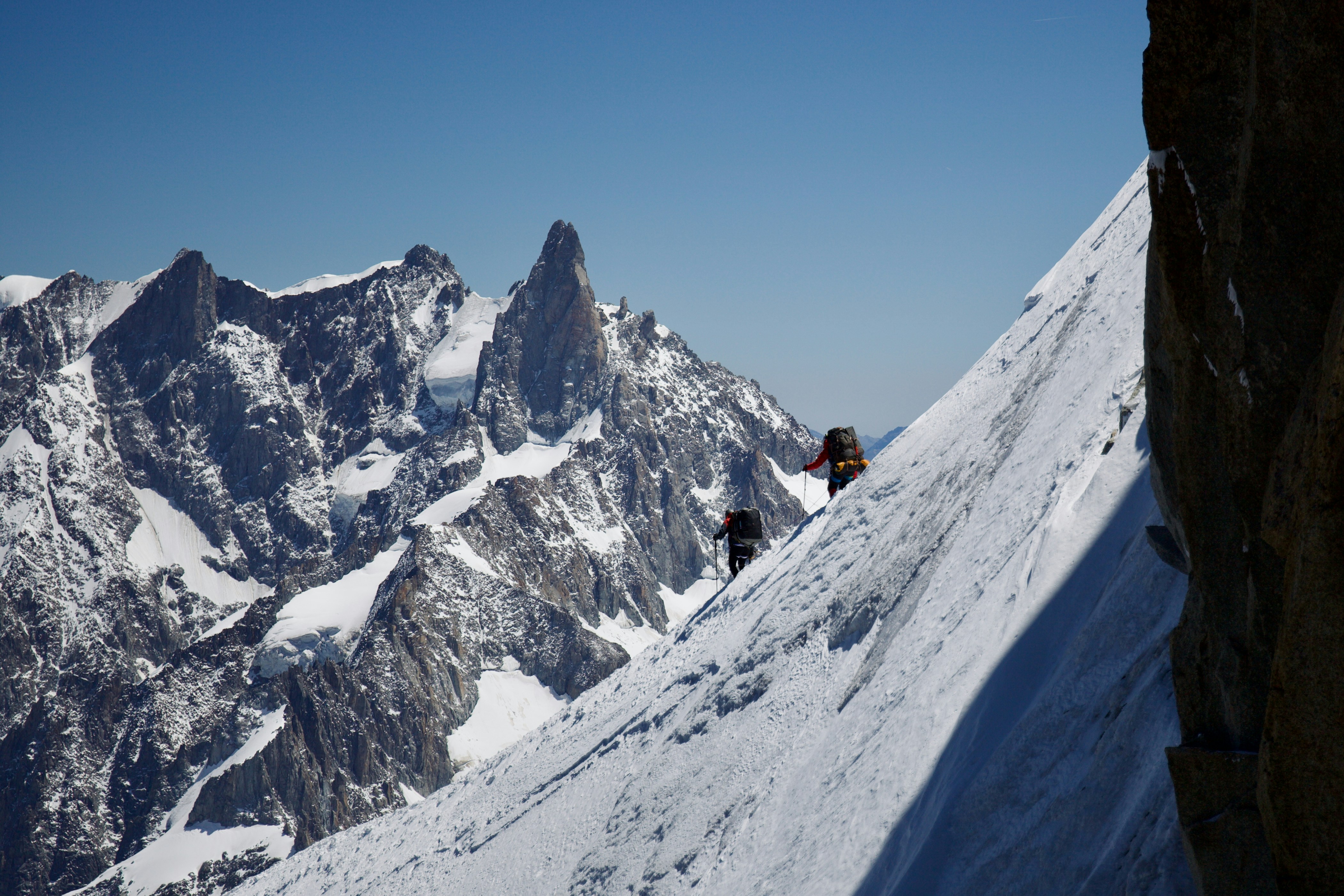 Climbers traverse a snowy mountain ridge.
