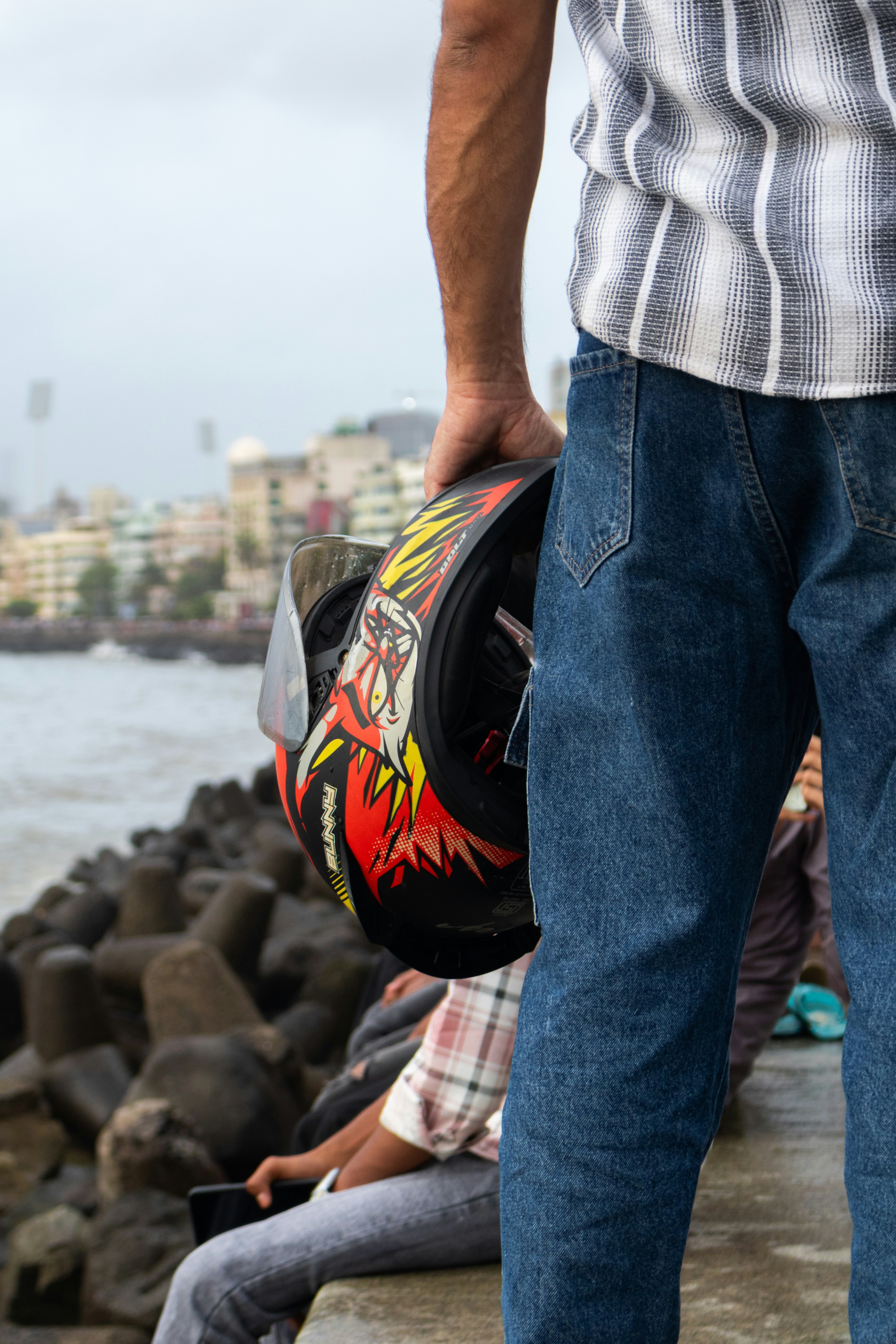 A man holds his helmet near the seaside.