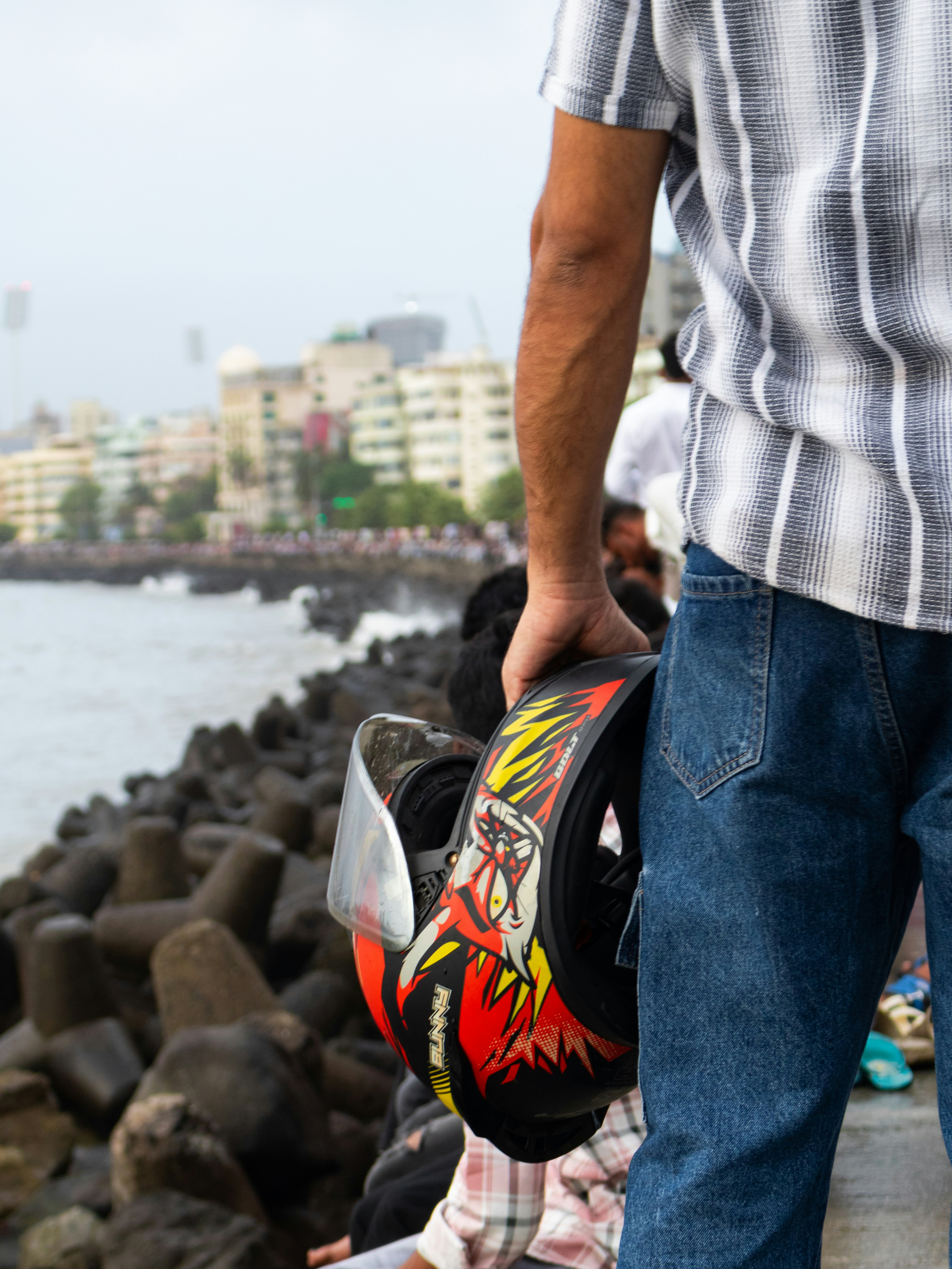 Man holds motorcycle helmet near the water.