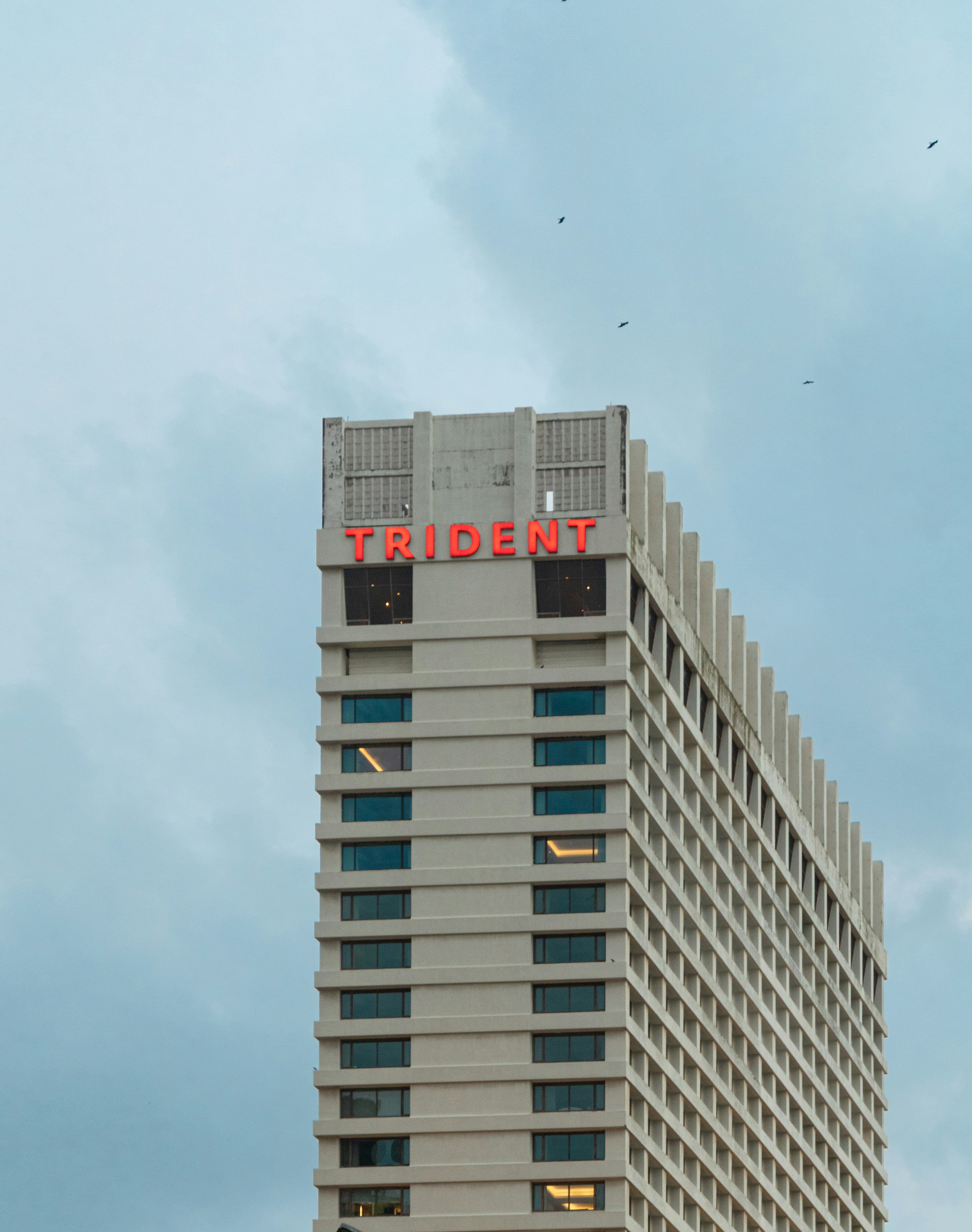 The trident hotel is tall against the cloudy sky.