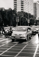 Cars and a motorcycle navigate a city intersection.