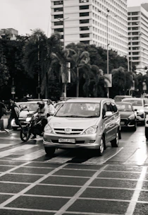 Cars and a motorcycle navigate a city intersection.