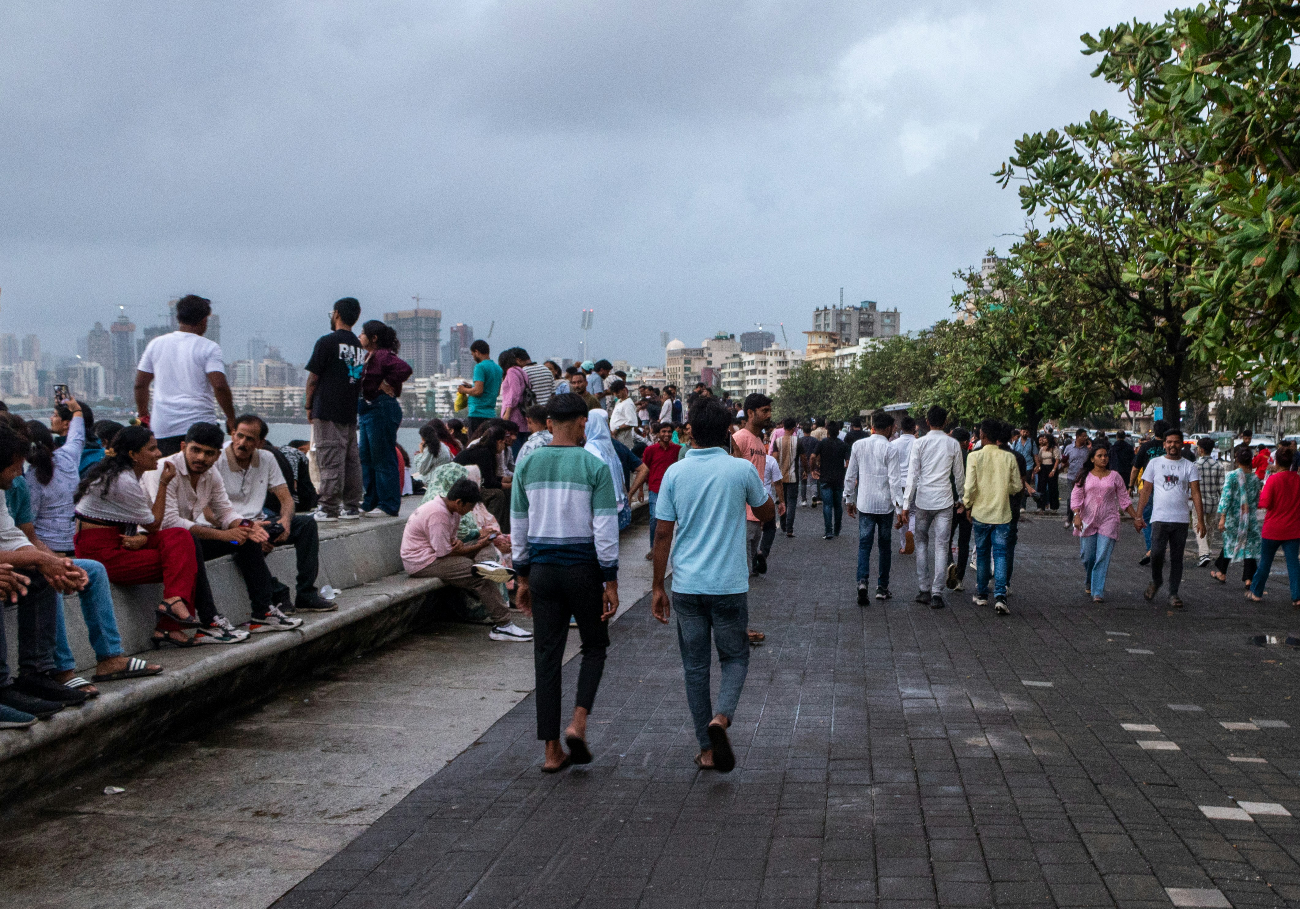 People stroll along a boardwalk by the water.