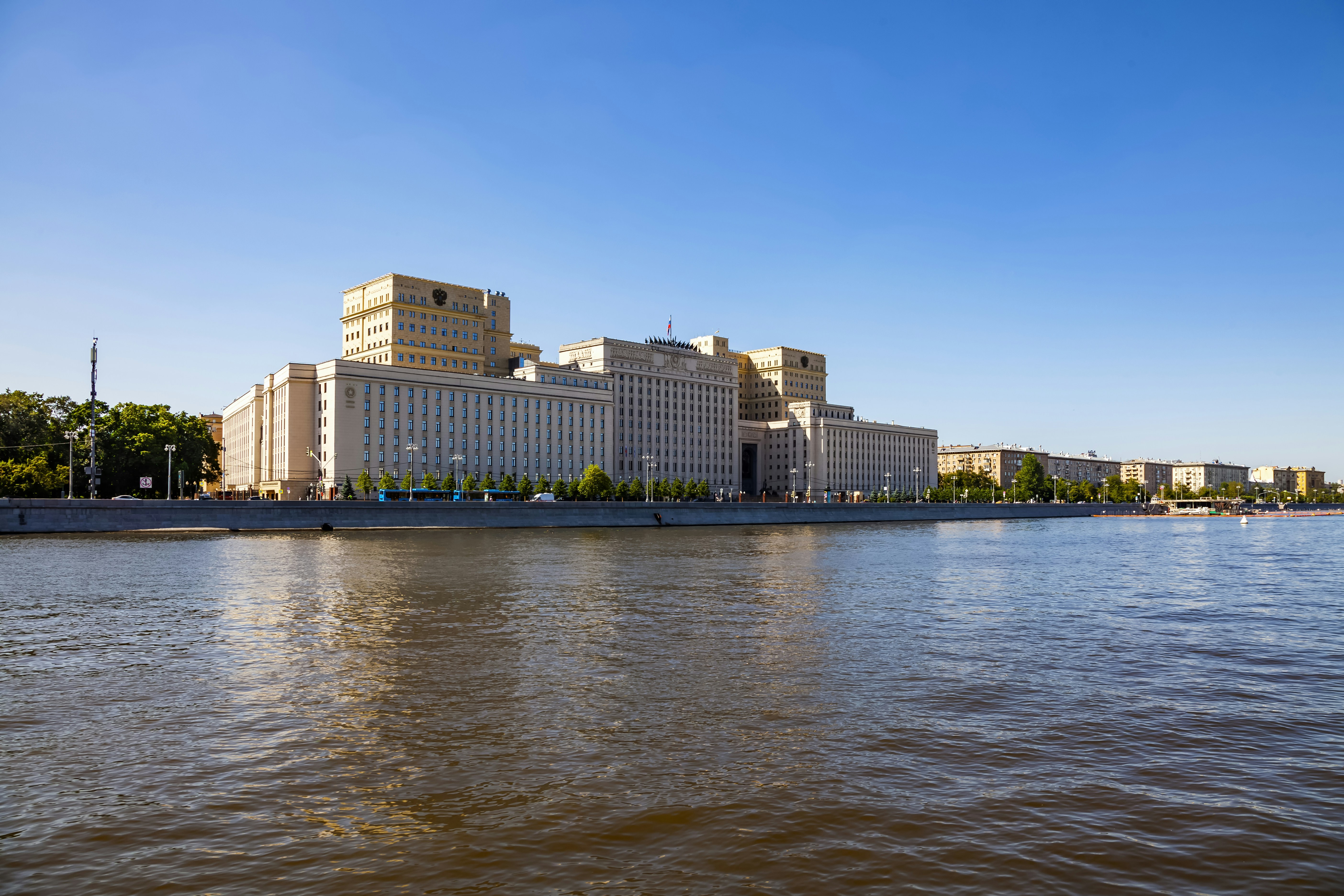 A large building sits beside a wide body of water.