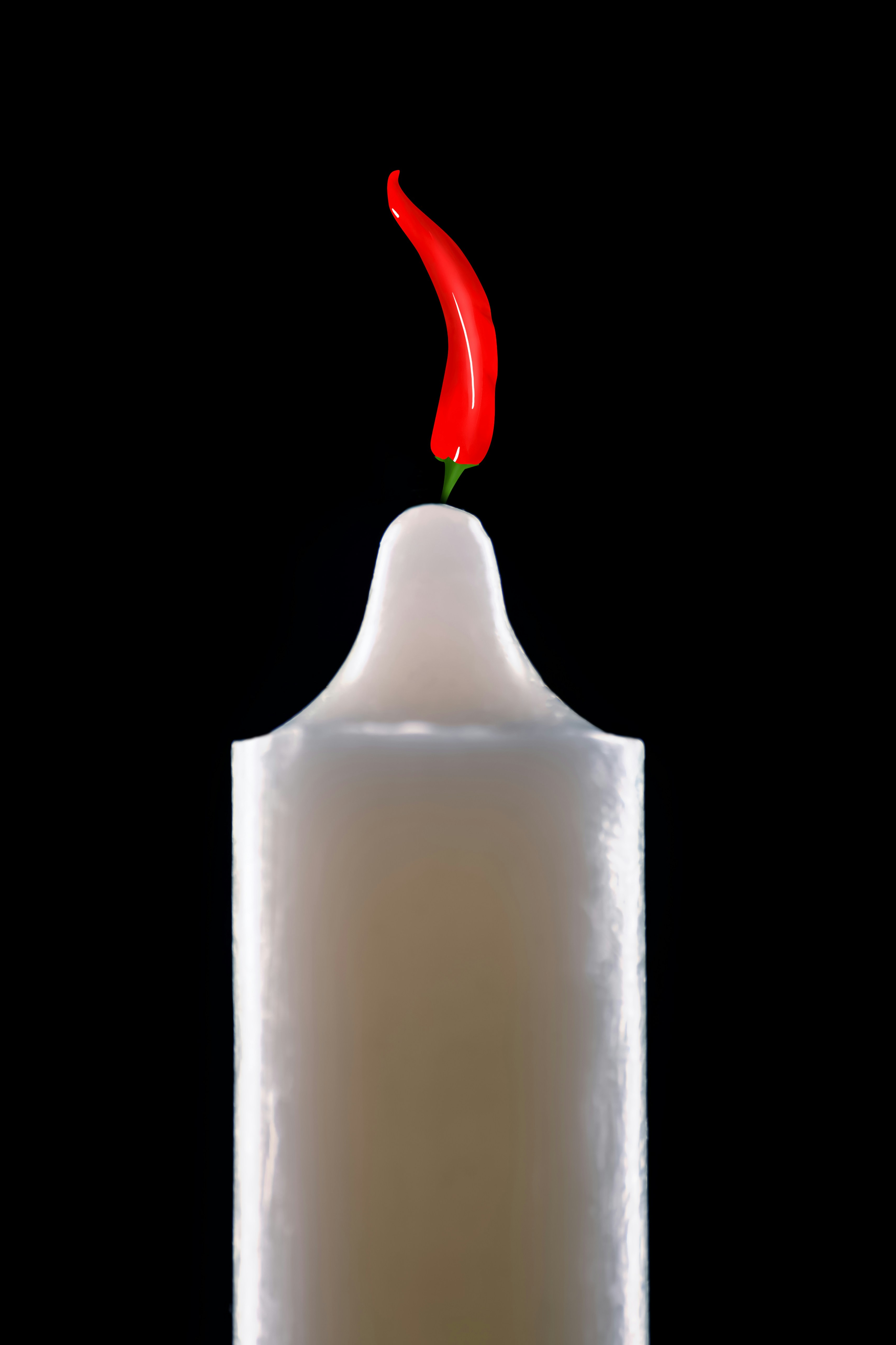 A chili pepper atop a white candle.