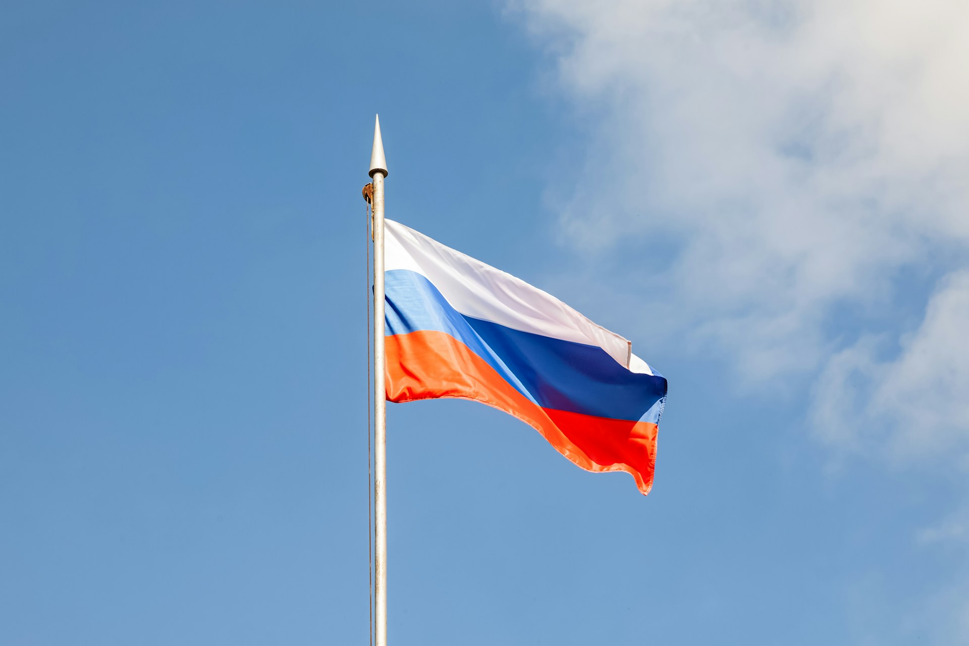 A russian flag waves against a blue sky.