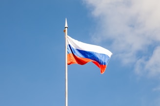 The russian flag waves against a clear, blue sky.