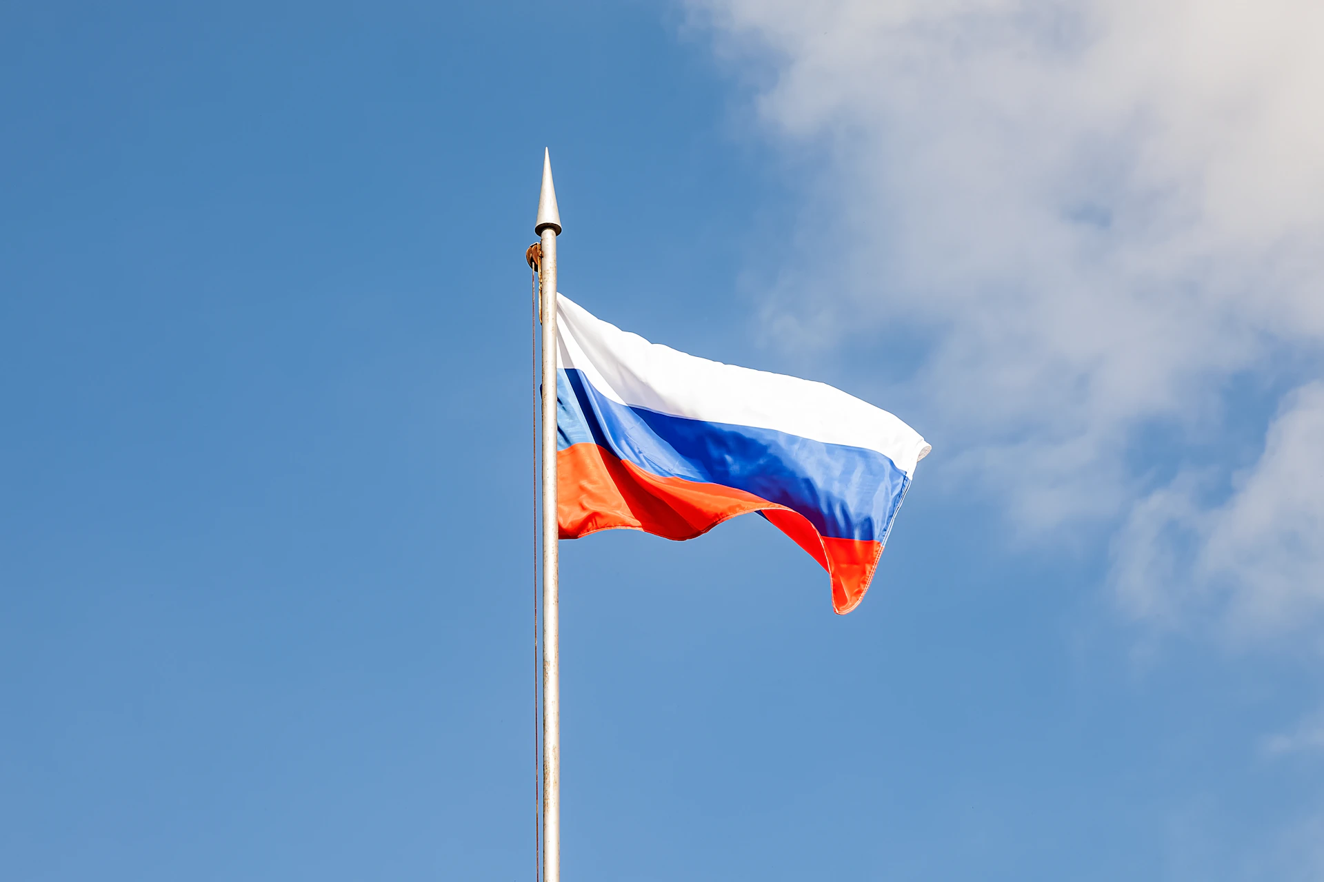 The russian flag waves against a clear, blue sky.