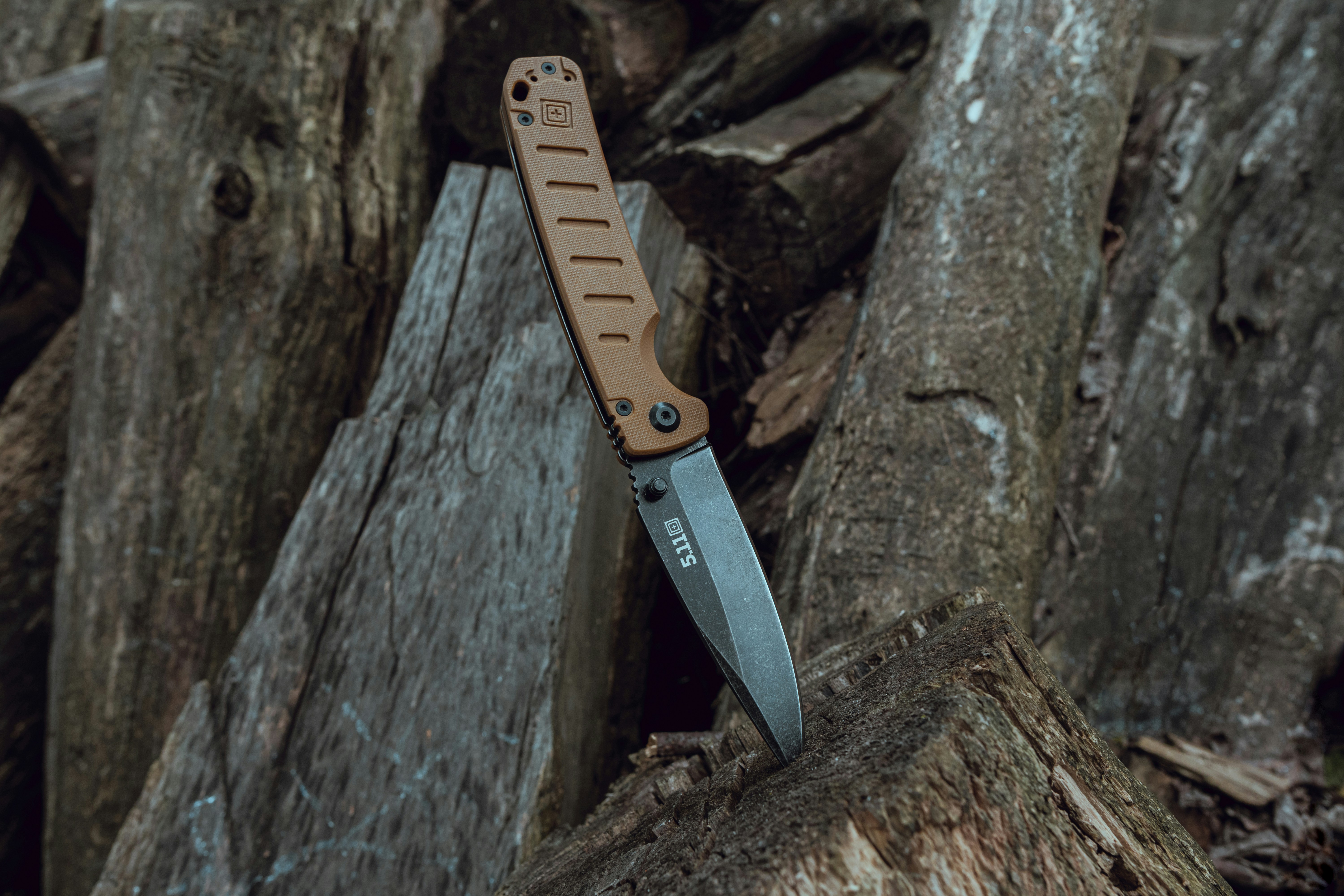 A knife is shown leaning against a log.