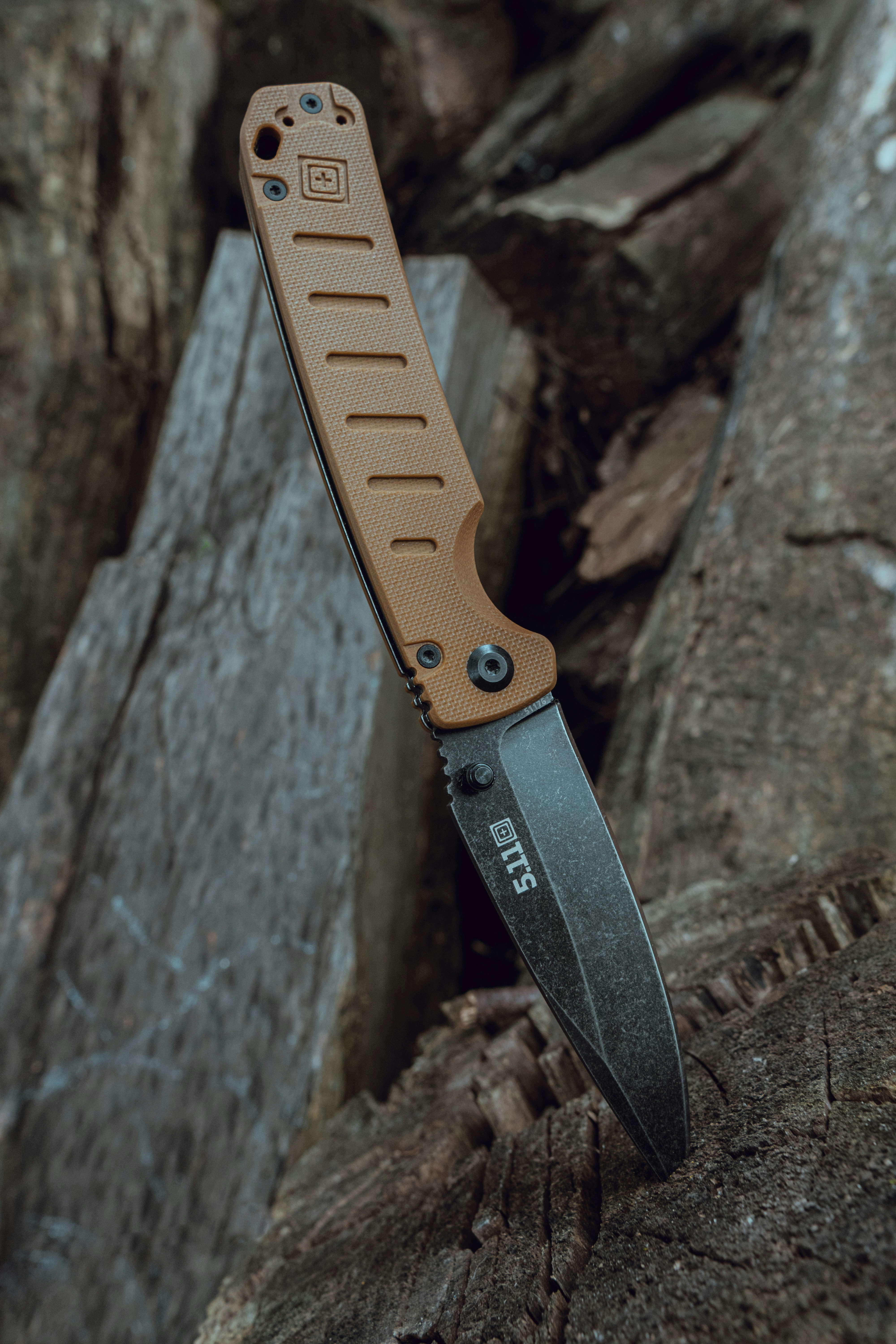 A pocket knife is shown leaning against wood.
