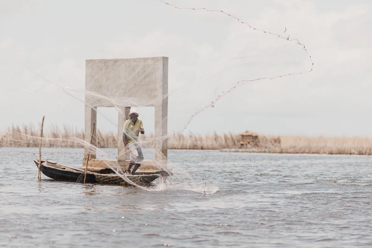 Un pêcheur lance son filet depuis une pirogue sur la lagune au Bénin