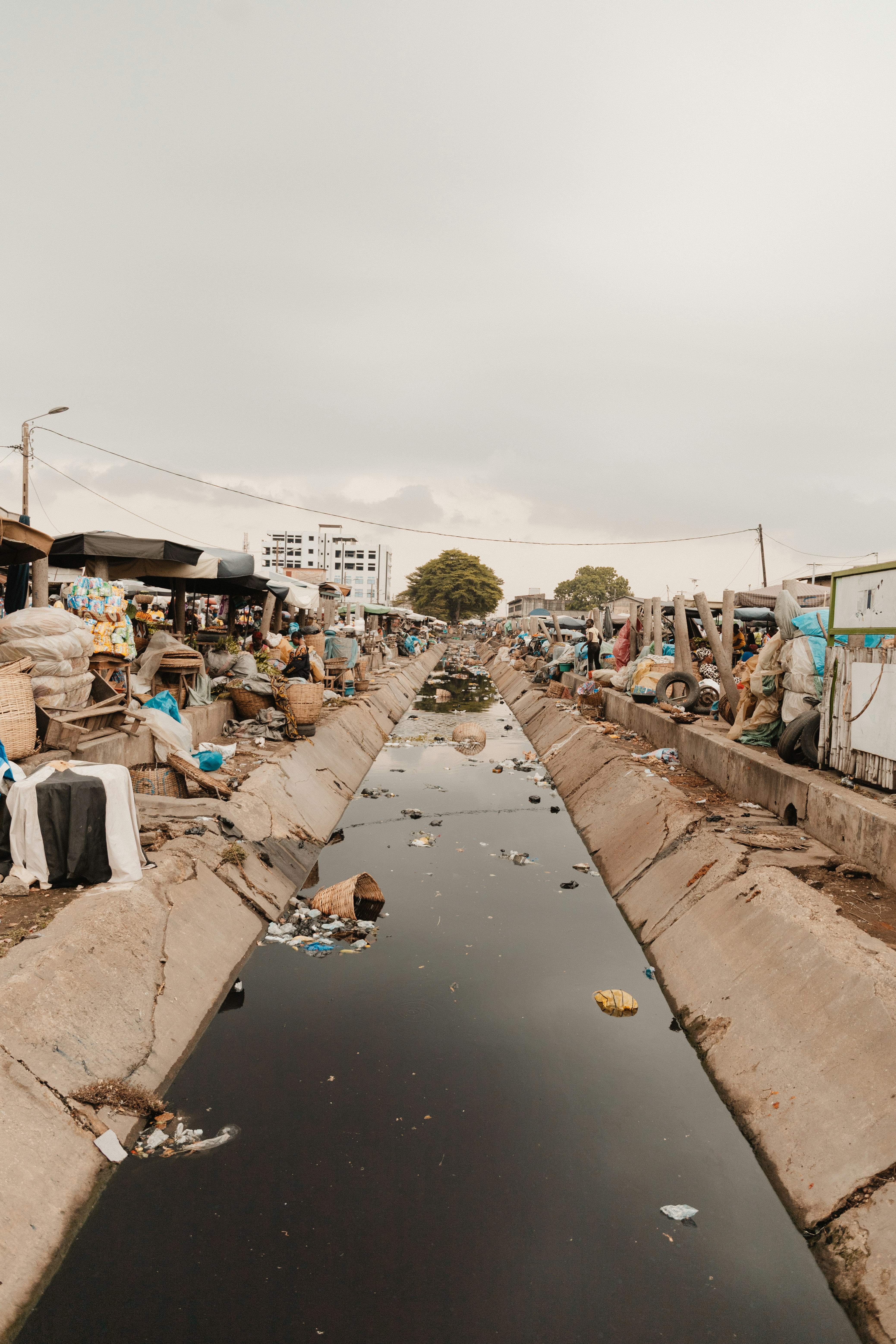 A polluted waterway surrounded by trash and buildings.