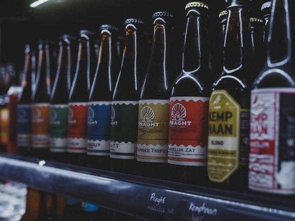 Bottles of beer are lined up on a shelf.