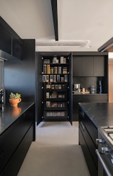 A modern kitchen with dark cabinets and pantry.