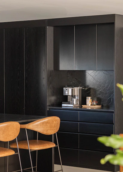 Modern kitchen with black cabinetry and stools.