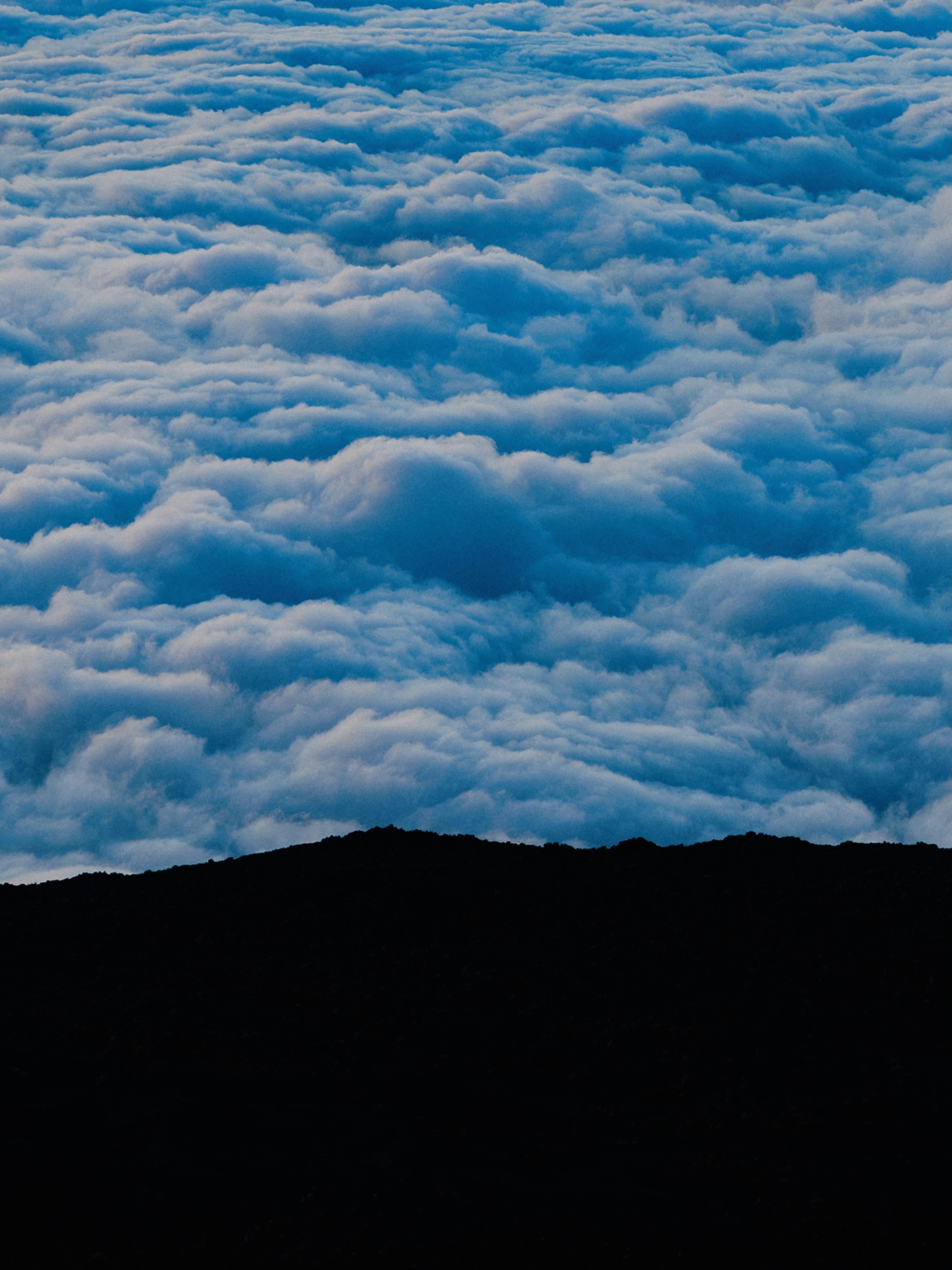 Clouds cover a mountain range in the beautiful sky.