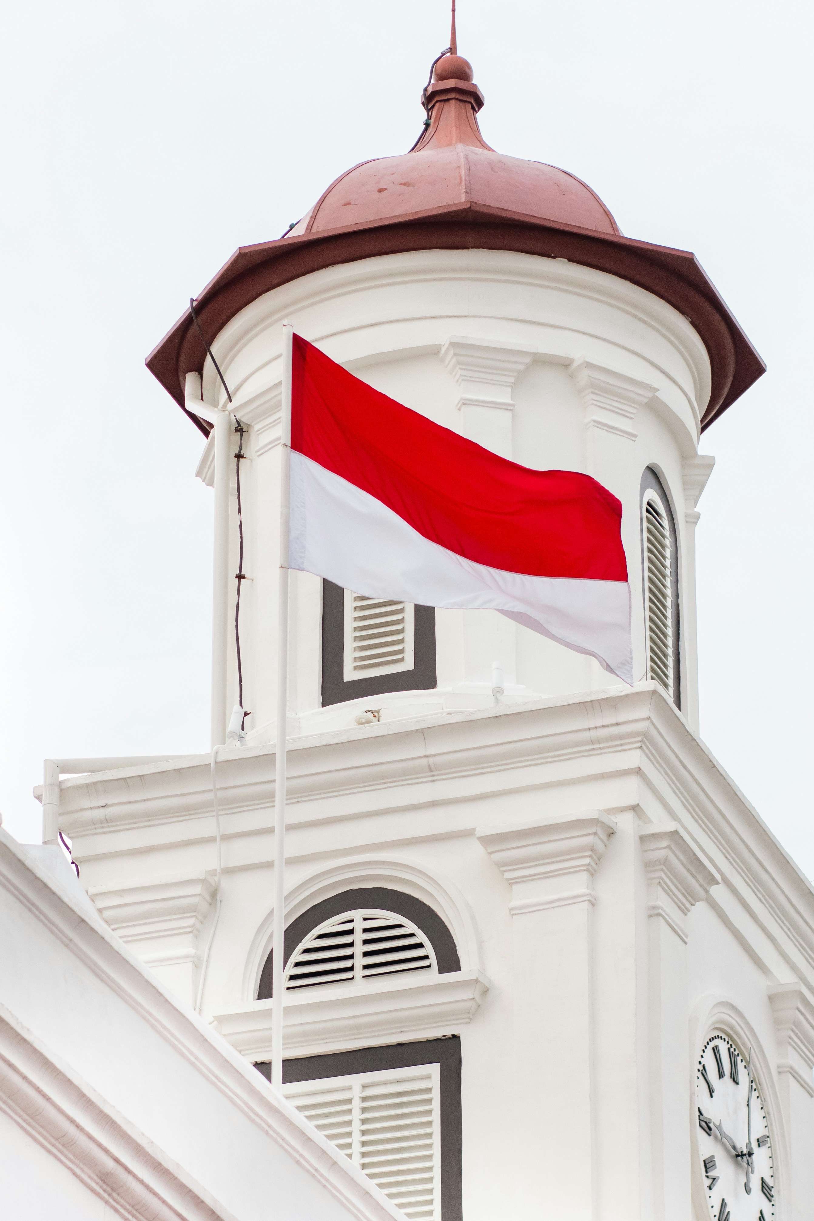 The indonesian flag waves proudly from a building.