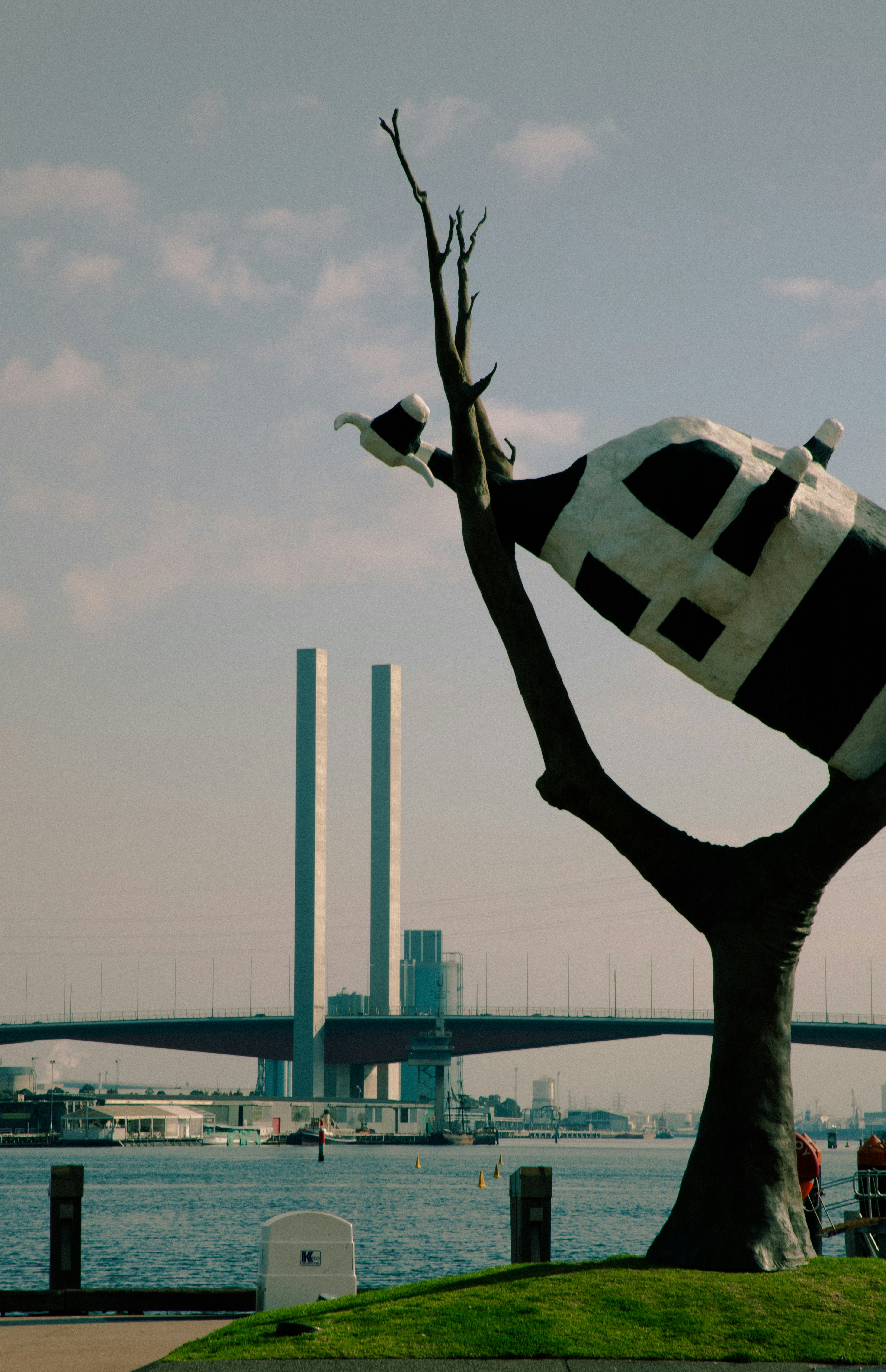 A sculpture with a city bridge in the background.